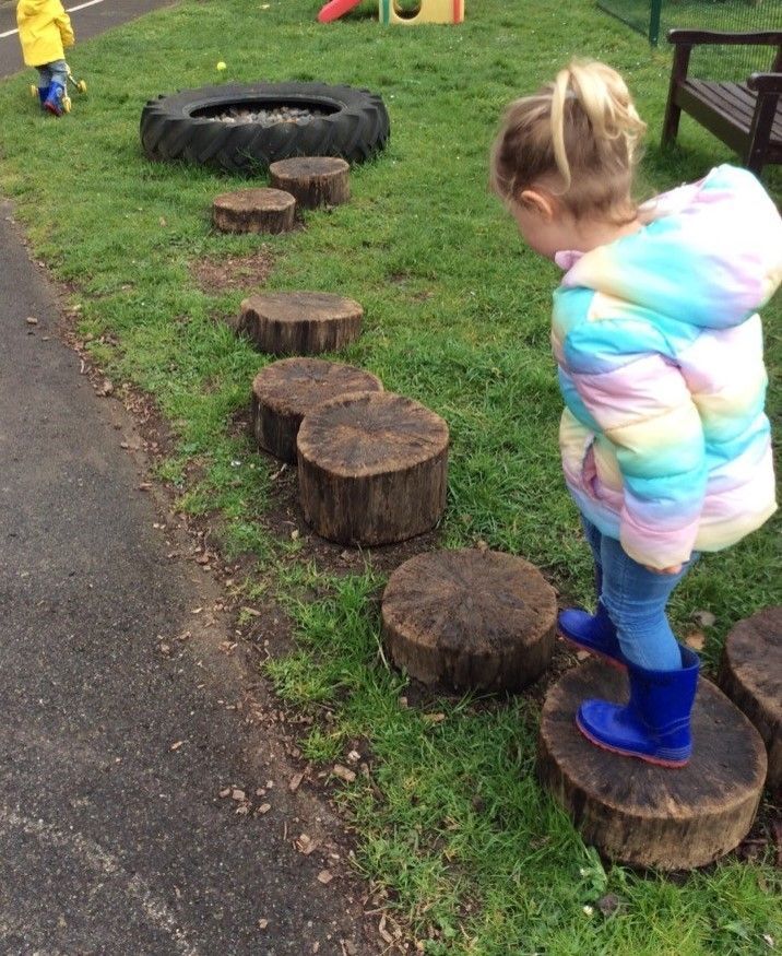 A little girl is standing on a row of logs.