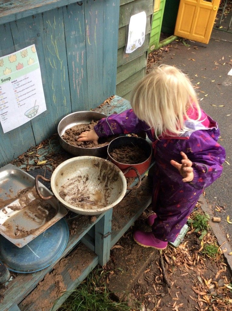 A little girl is playing in the mud with pots and pans.