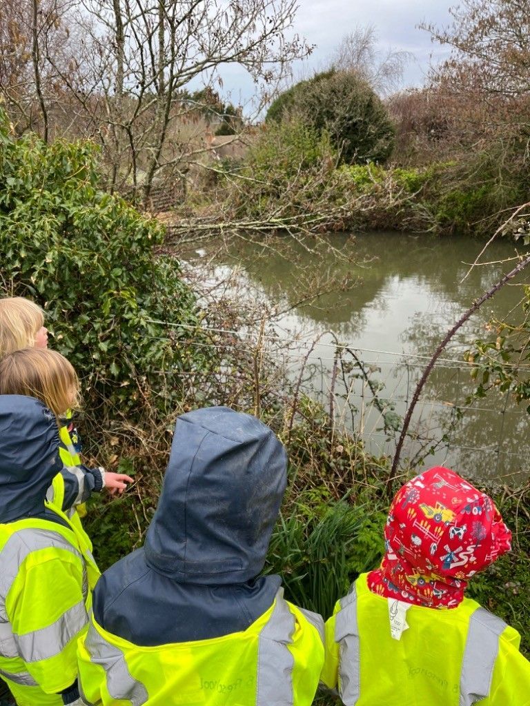 A group of children in yellow vests are looking at a river.