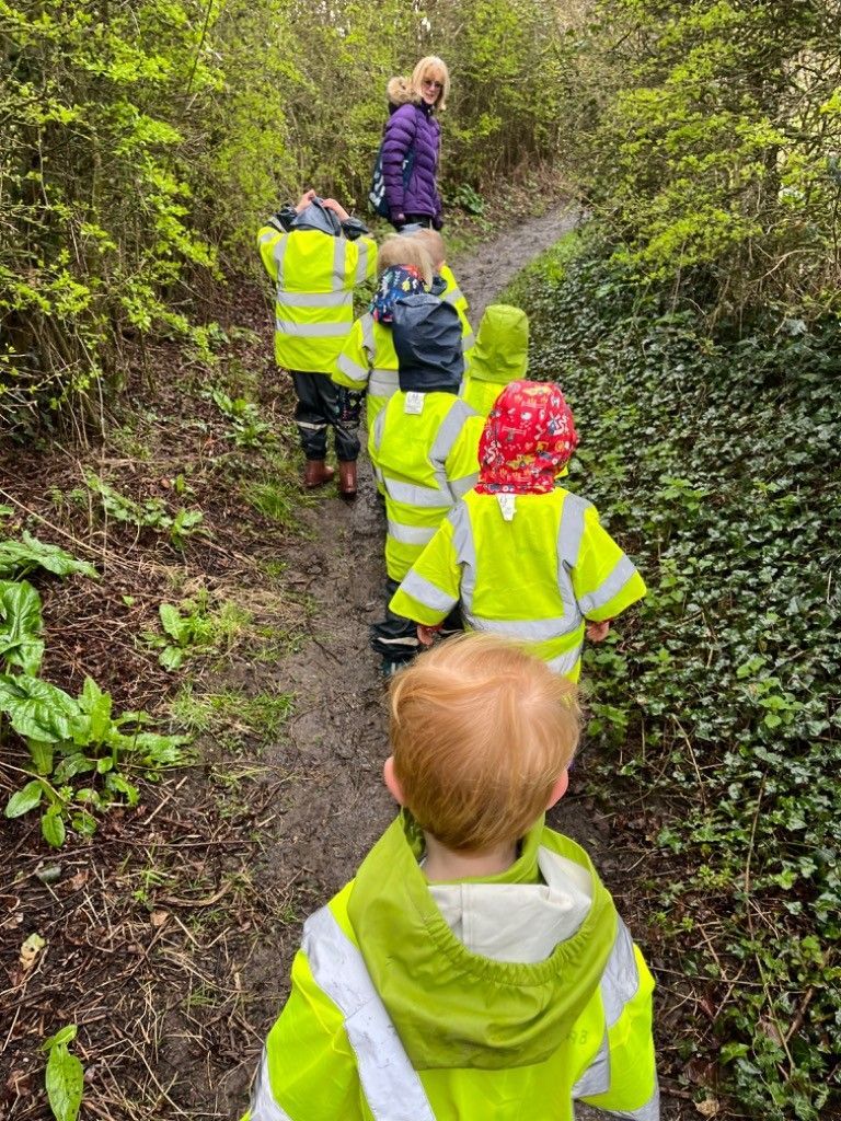 A group of children are walking down a path in the woods.