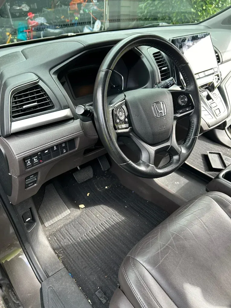 Car interior with black leather seats, steering wheel, dashboard, and center console visible from the driver’s side.
