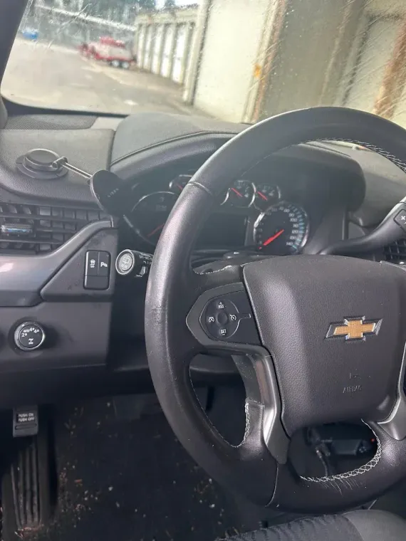 Chevrolet steering wheel and dashboard inside a car, with the road visible ahead through the windshield.