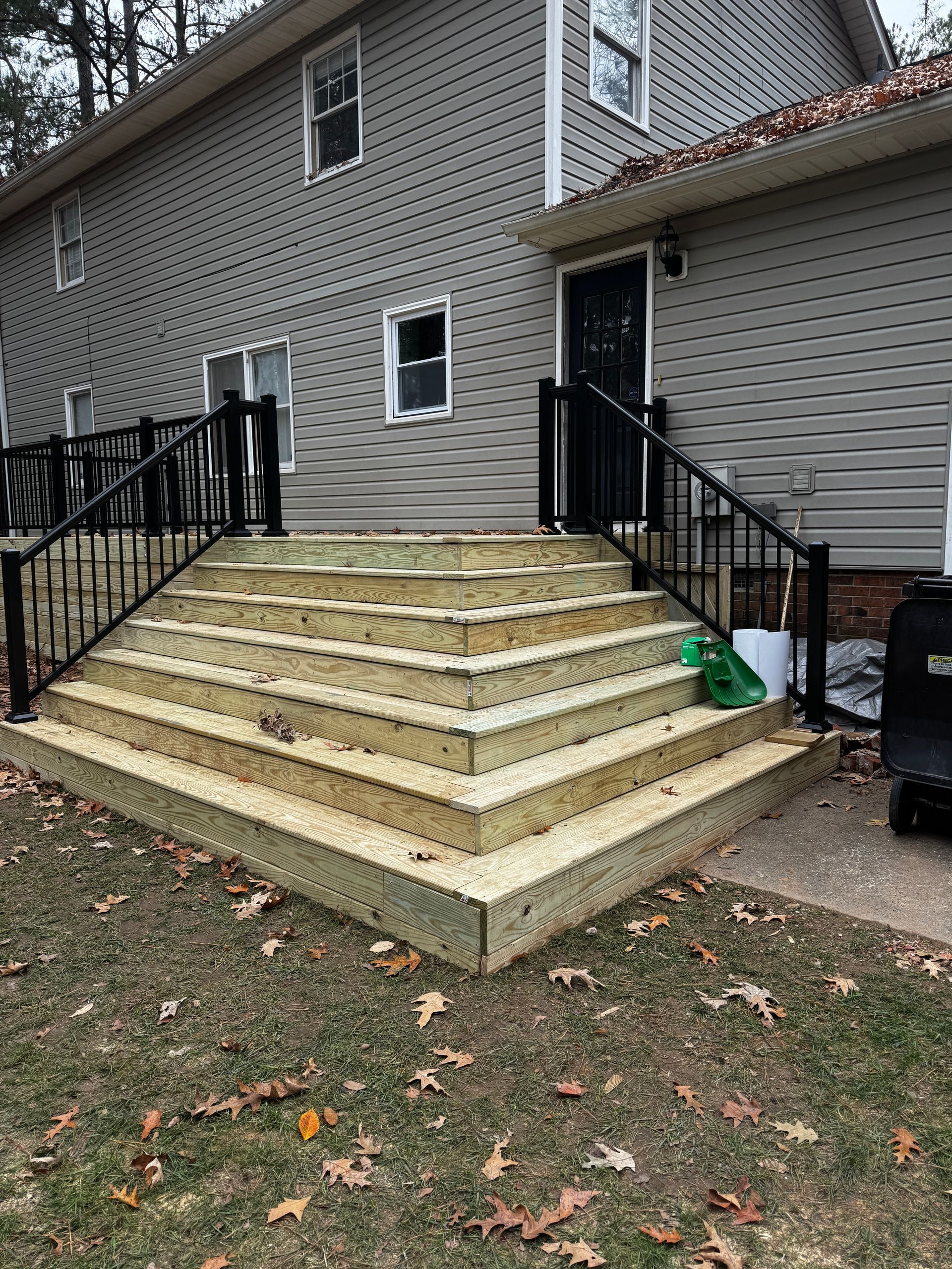 A wooden deck with stairs leading up to a house.