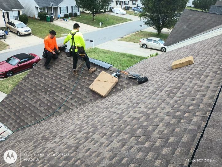 Two men are working on the roof of a house.