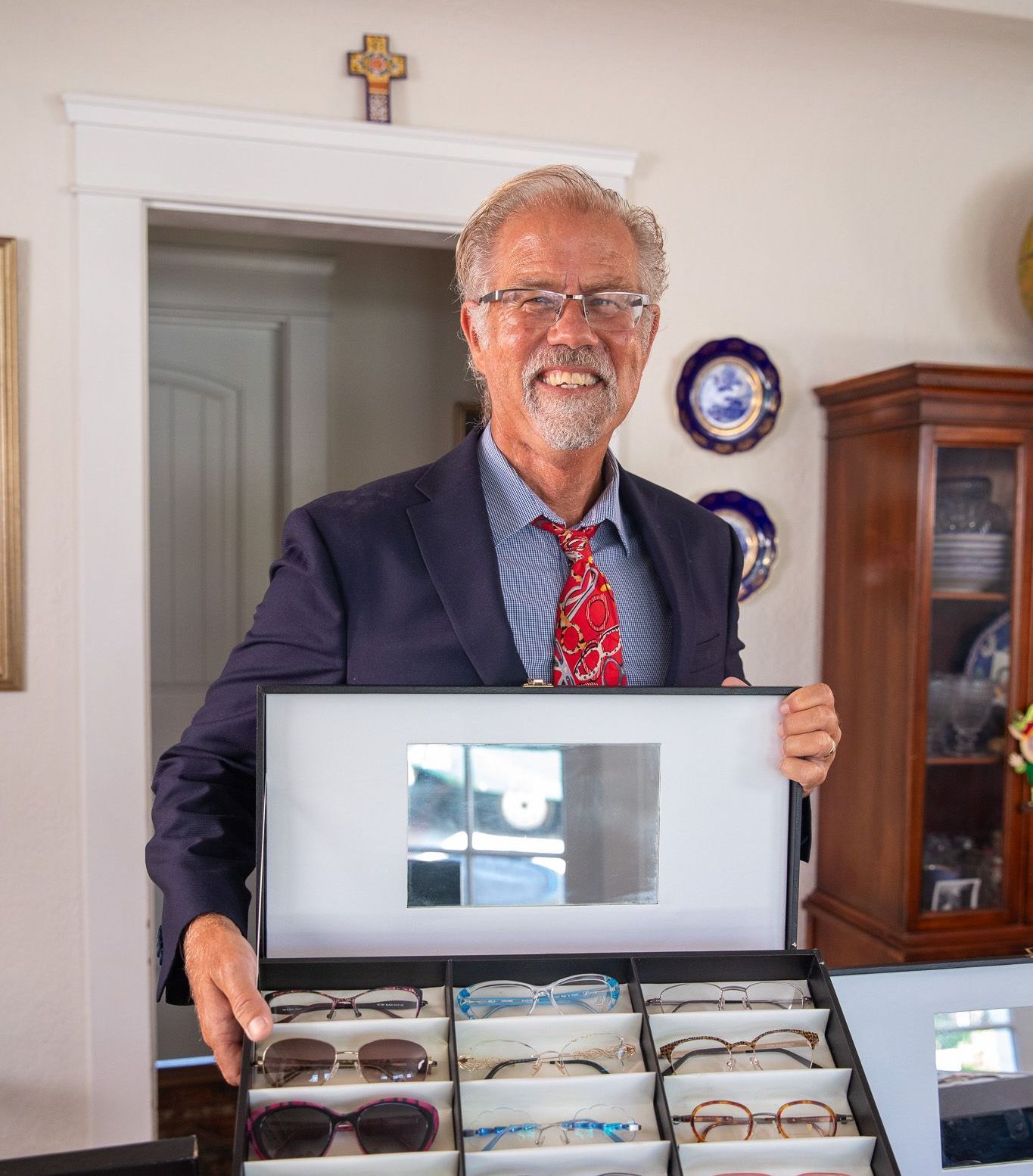 A man in a suit and tie is holding a box of glasses