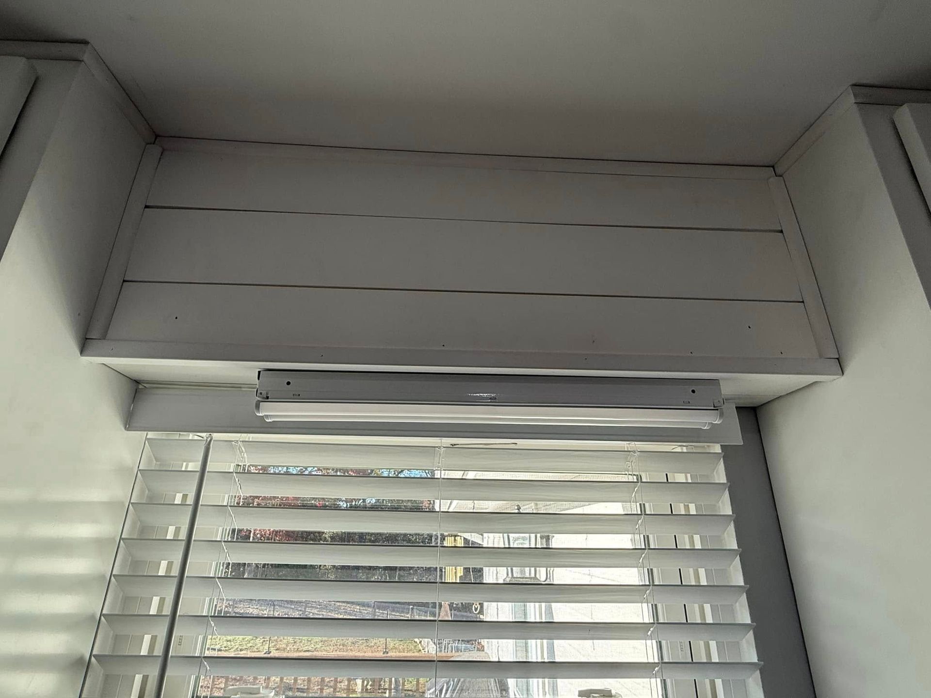 A window with blinds and a light on the ceiling