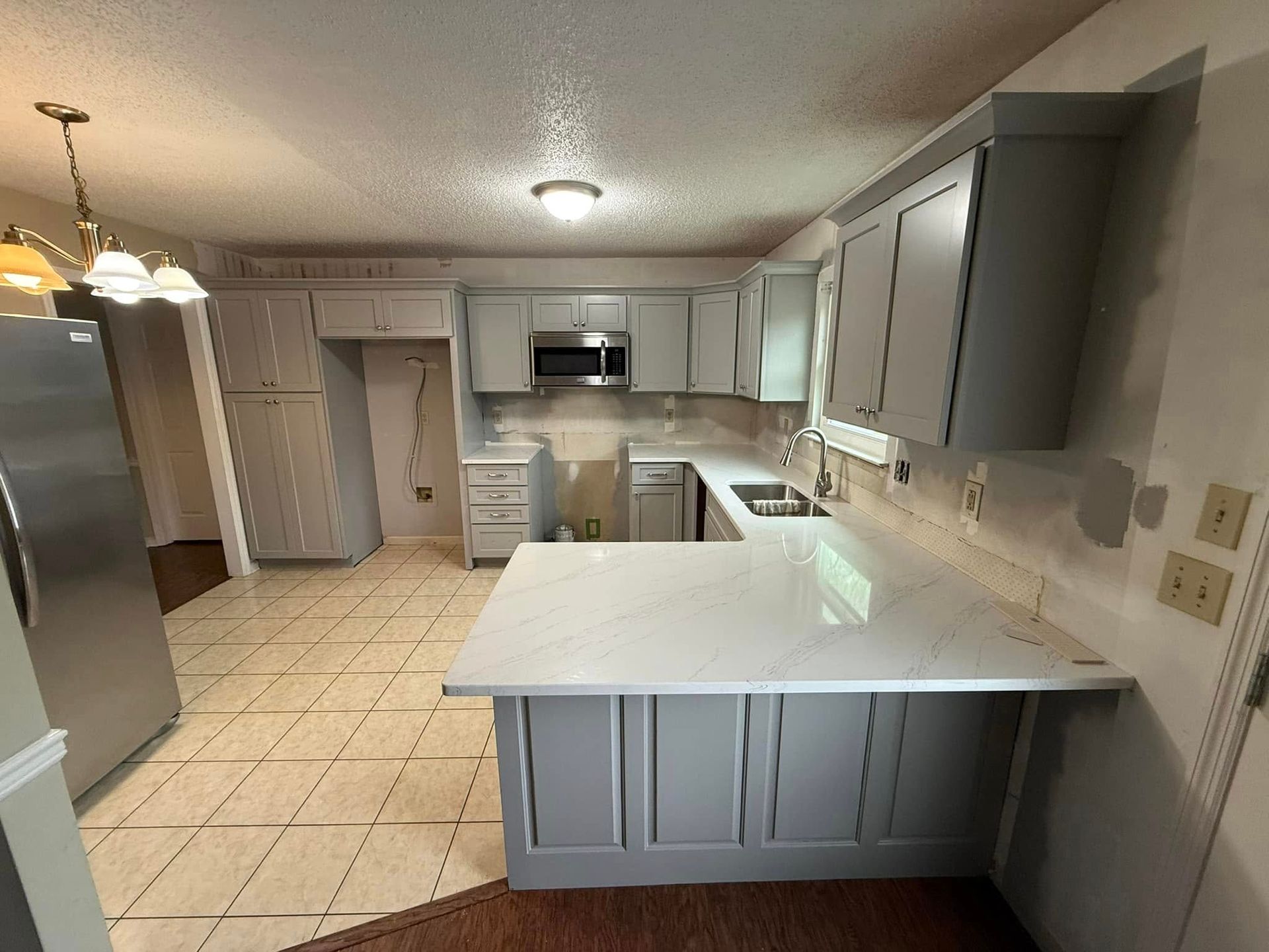 A kitchen with gray cabinets and white counter tops