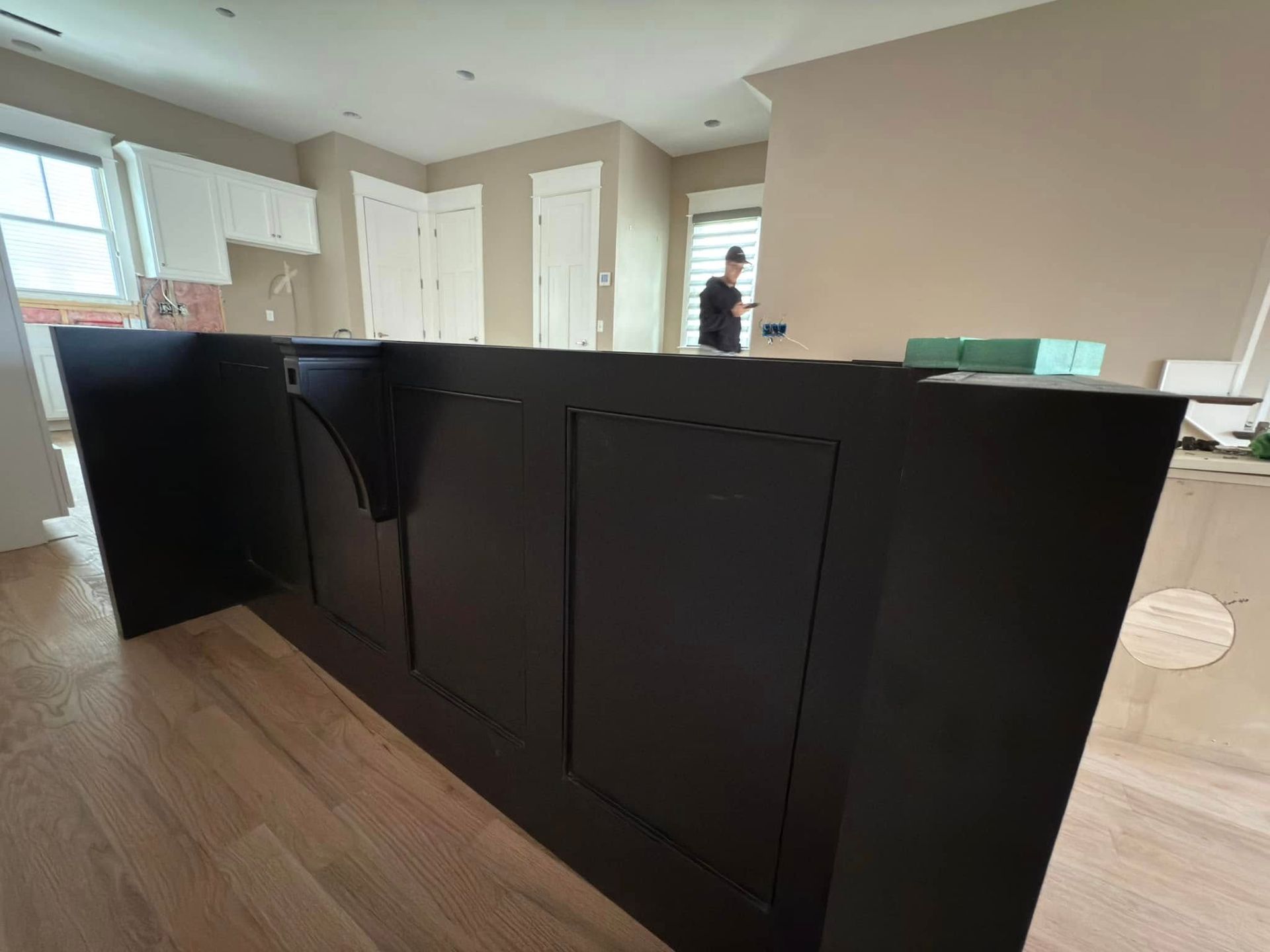 A man is standing behind a black counter in a kitchen.