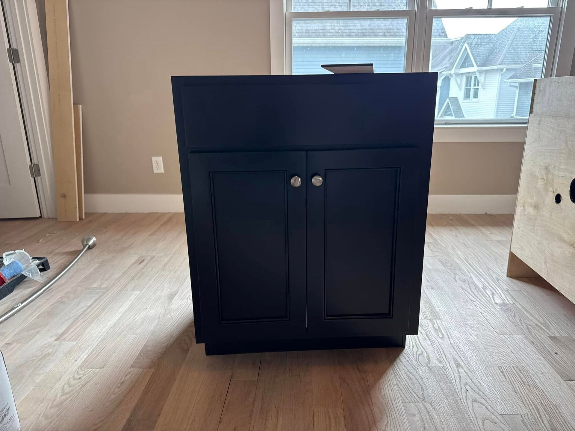 A black cabinet is sitting in a room next to a window.