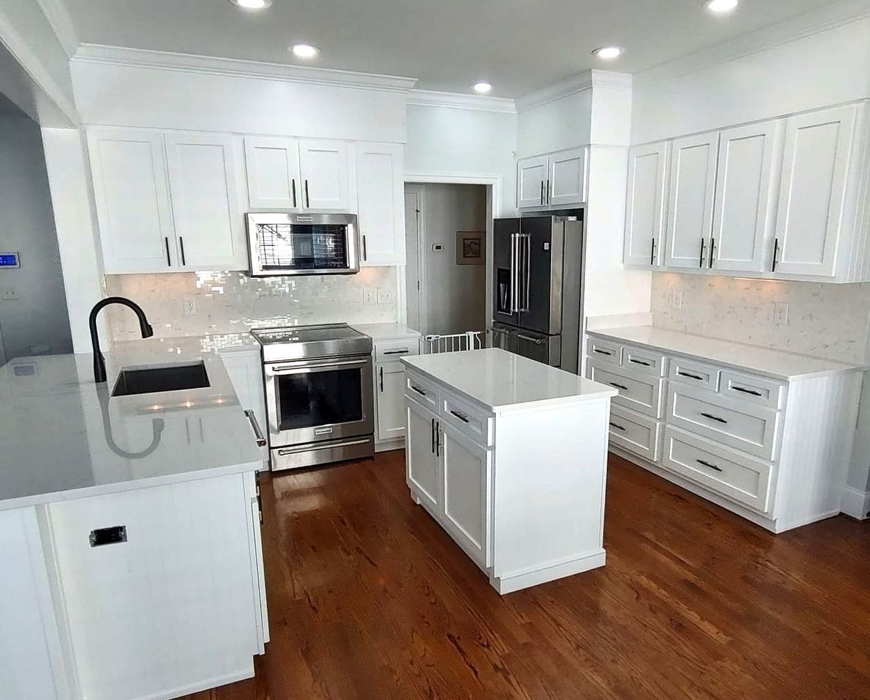 A kitchen with white cabinets , stainless steel appliances , and a large island.