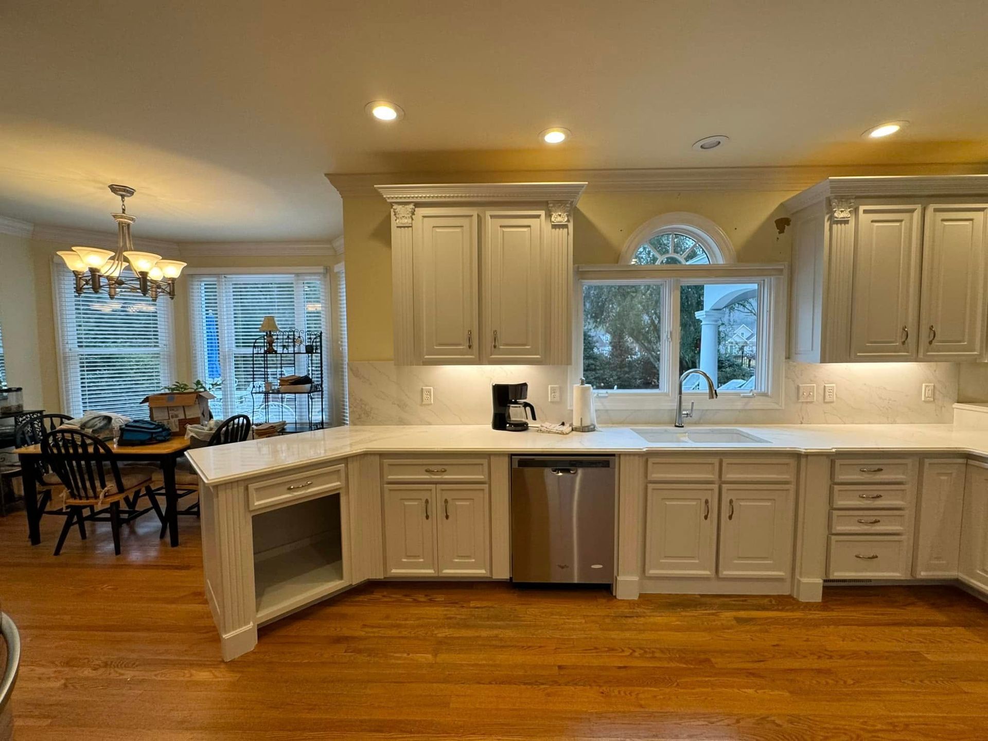 Spacious kitchen with gray cabinets, white countertops, and stainless steel appliances. Hardwood floors and natural light.