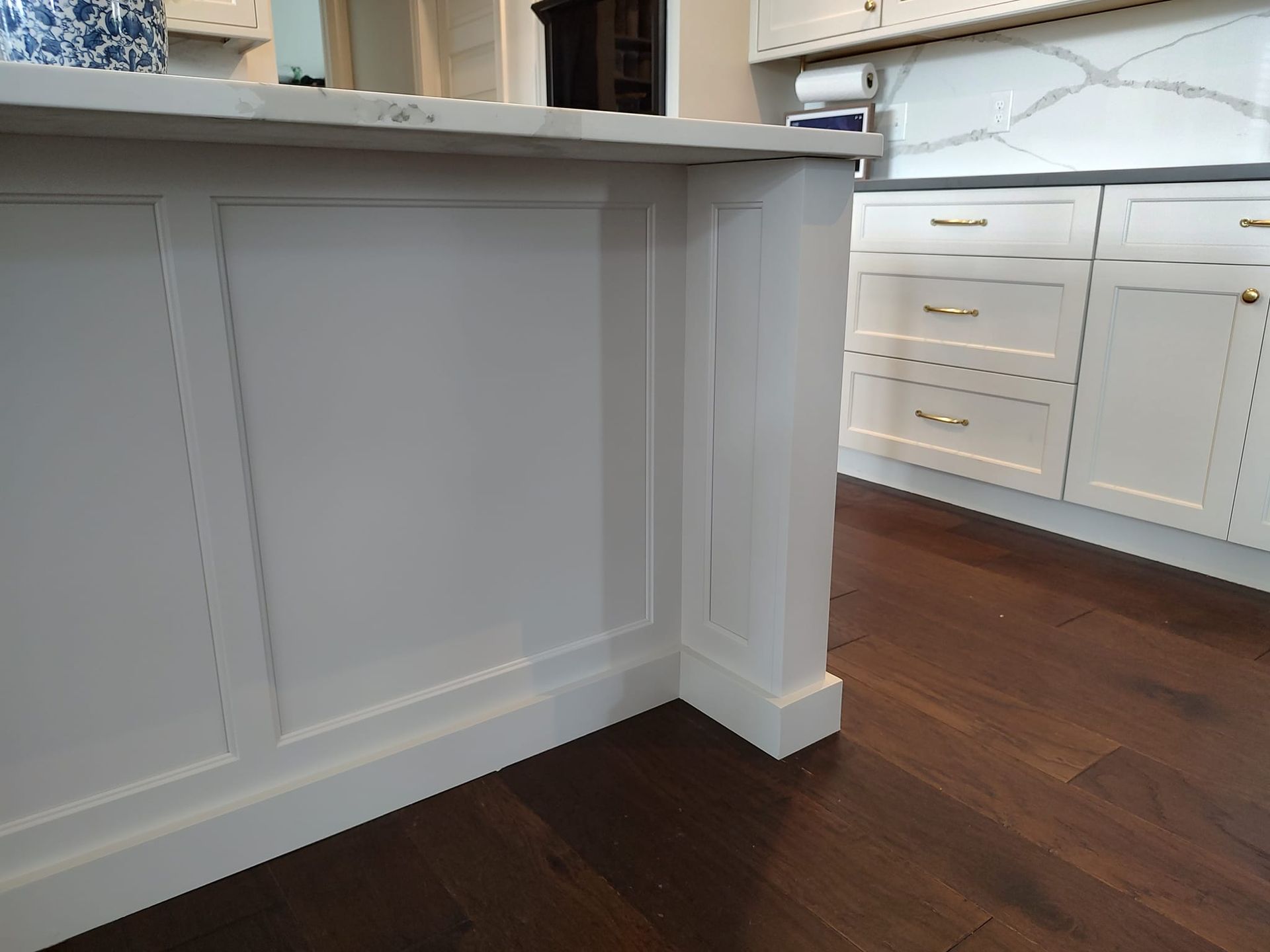 A kitchen with white cabinets and a wooden floor.