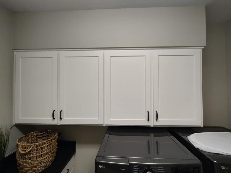 A laundry room with white cabinets and a washer and dryer.