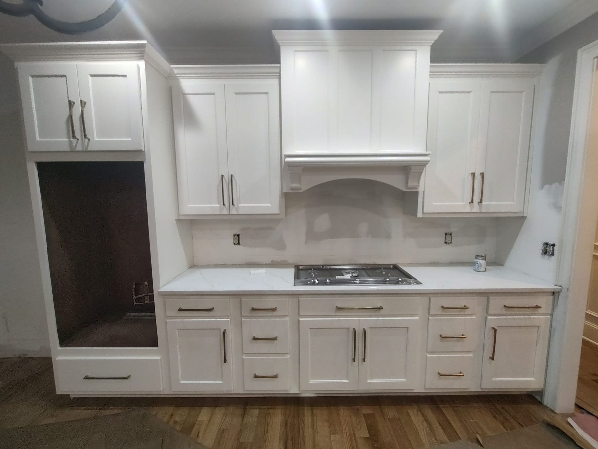 A kitchen with white cabinets and a stove top oven.