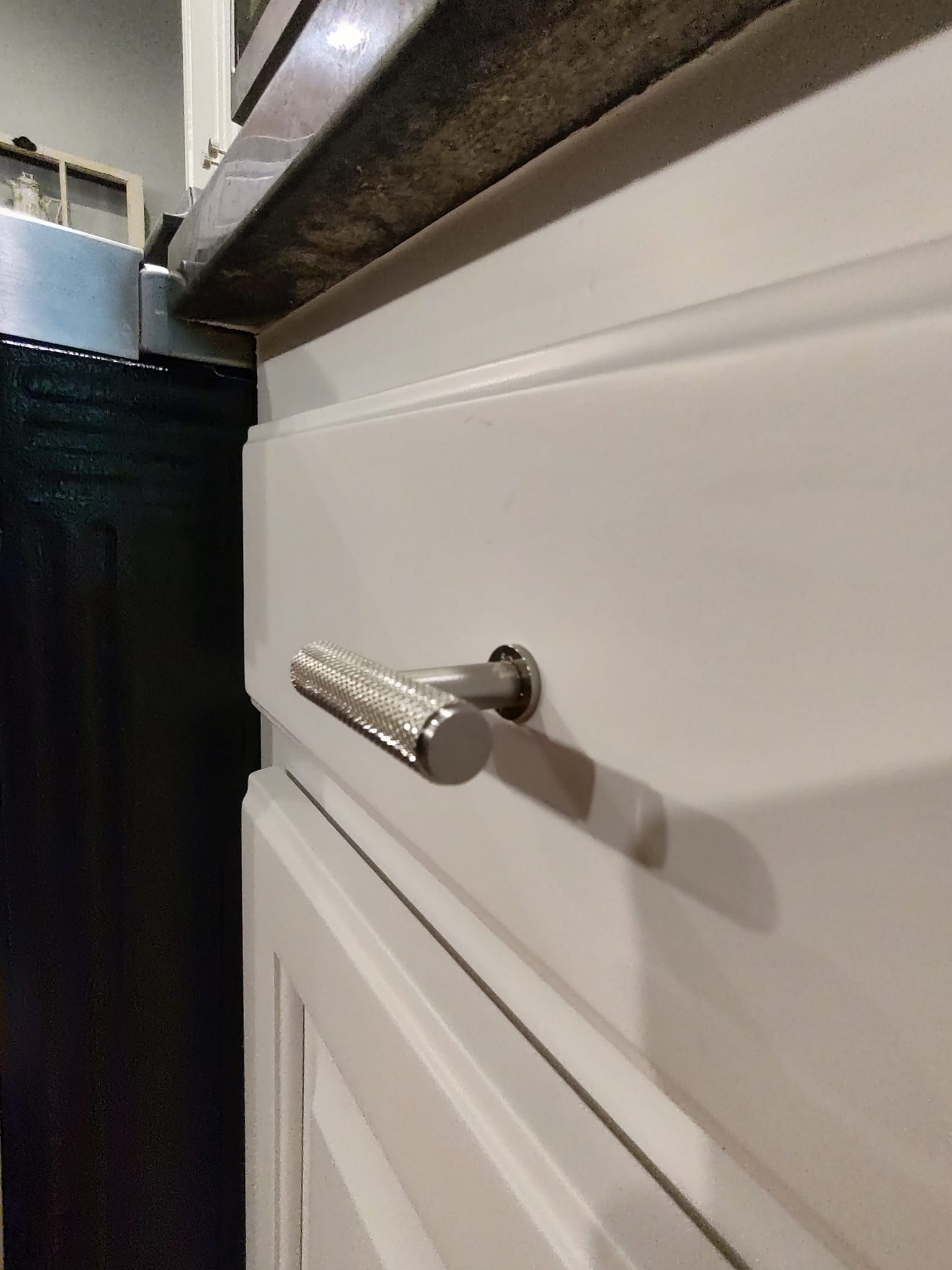 A close up of a white cabinet with a silver handle.