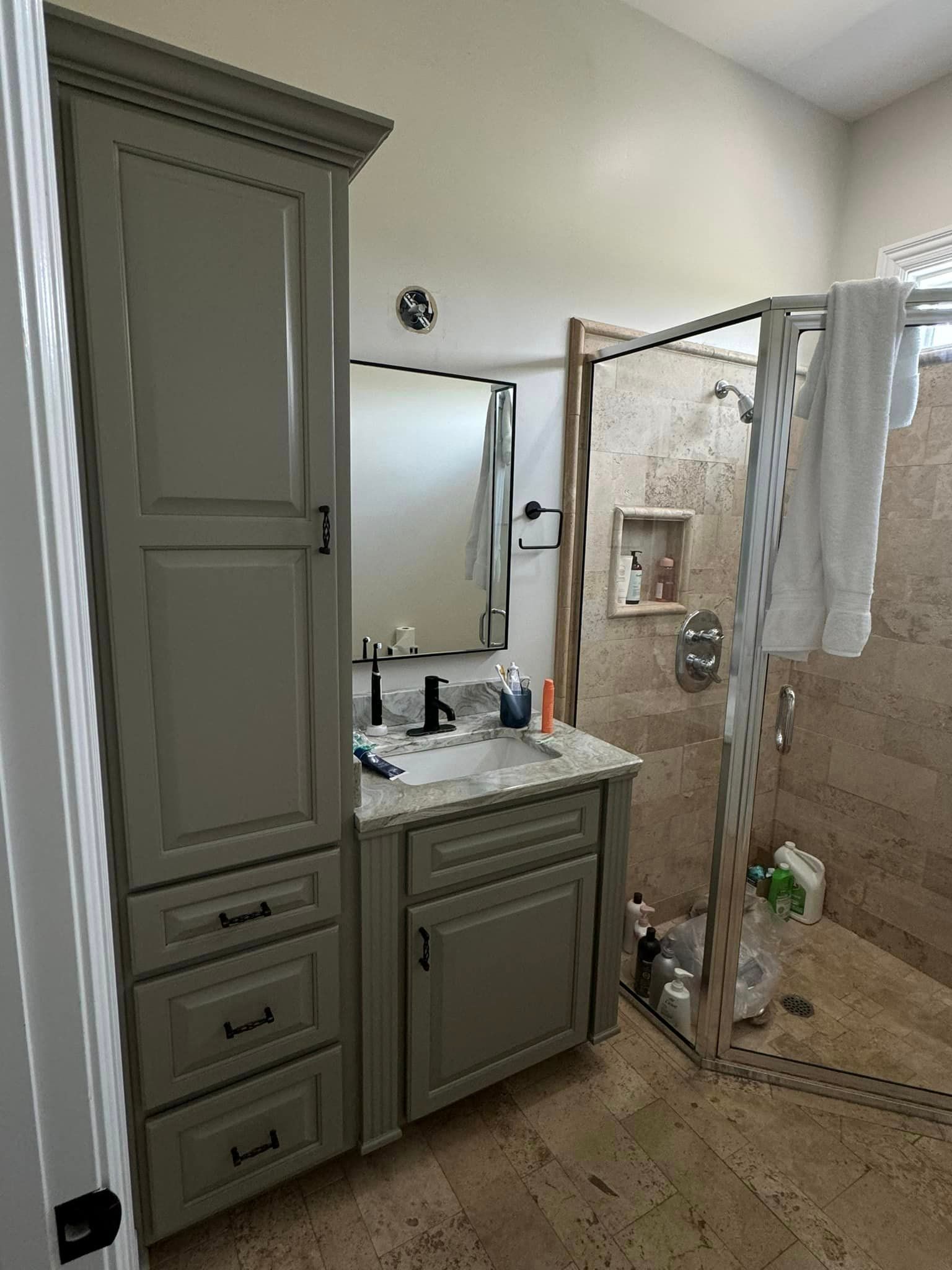 A bathroom with a sink , mirror and walk in shower.