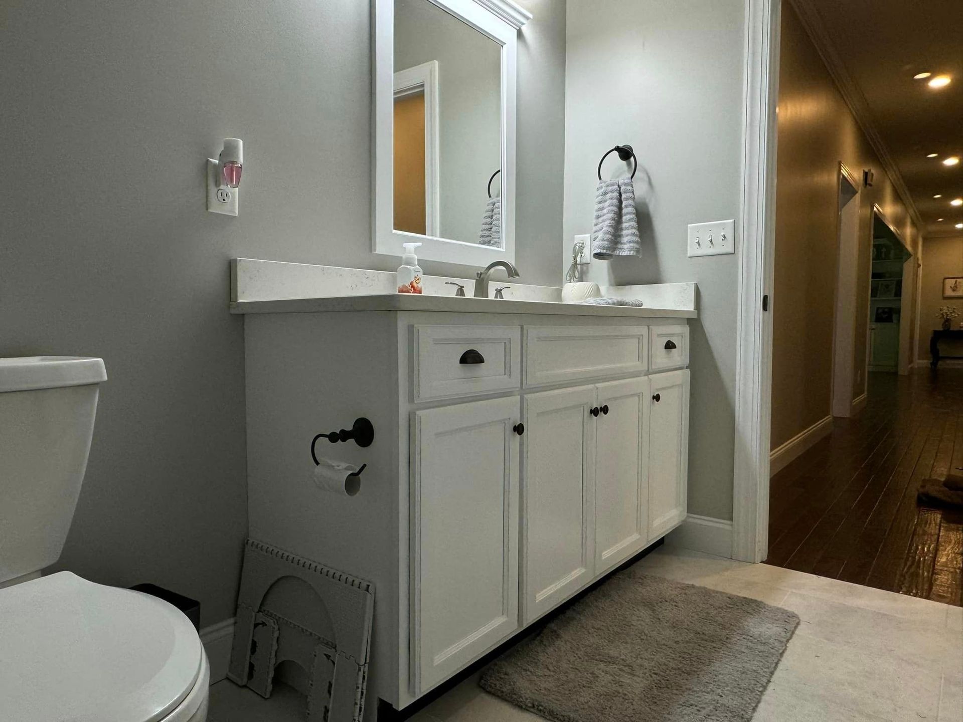 A bathroom with a toilet , sink and mirror.