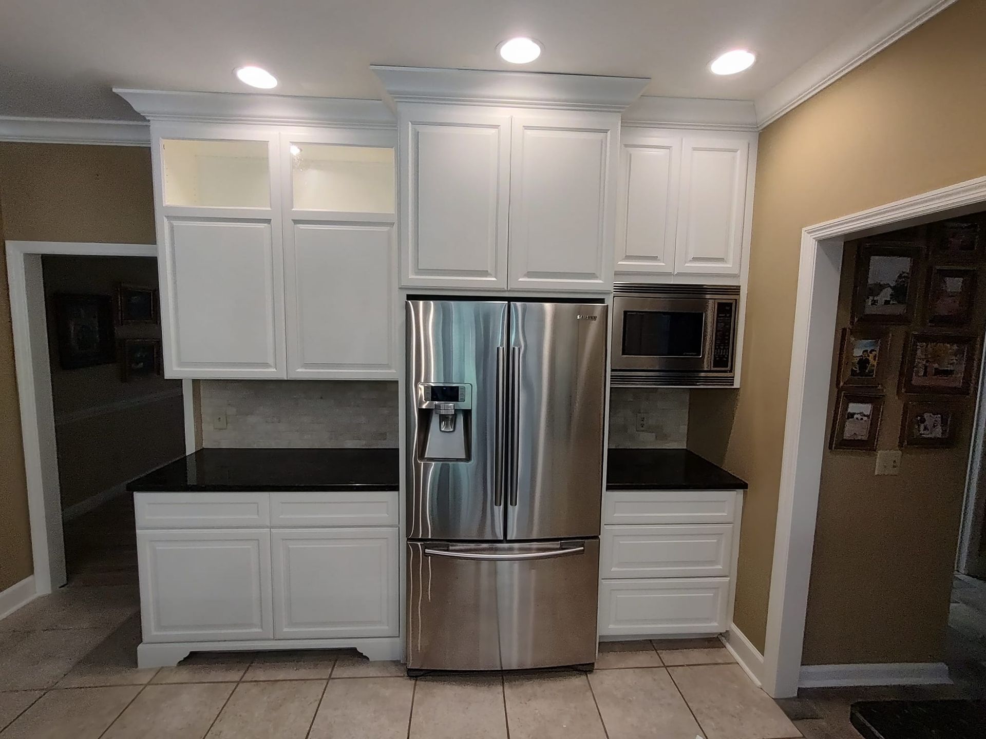 A kitchen with white cabinets and a stainless steel refrigerator