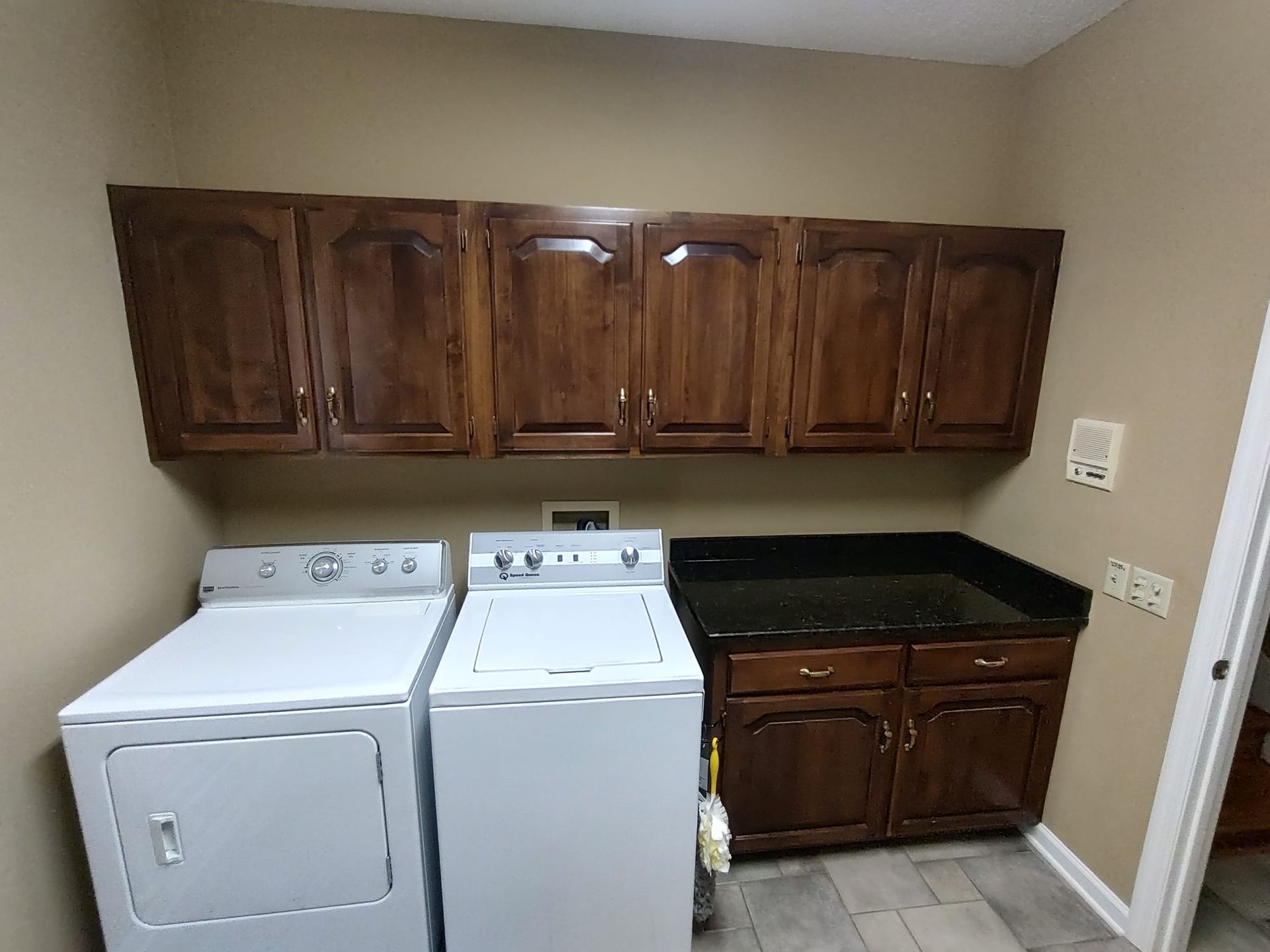 A laundry room with a washer and dryer and wooden cabinets.