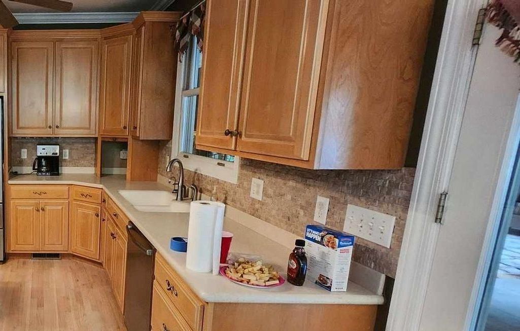 A kitchen with wooden cabinets , a sink , and a dishwasher.