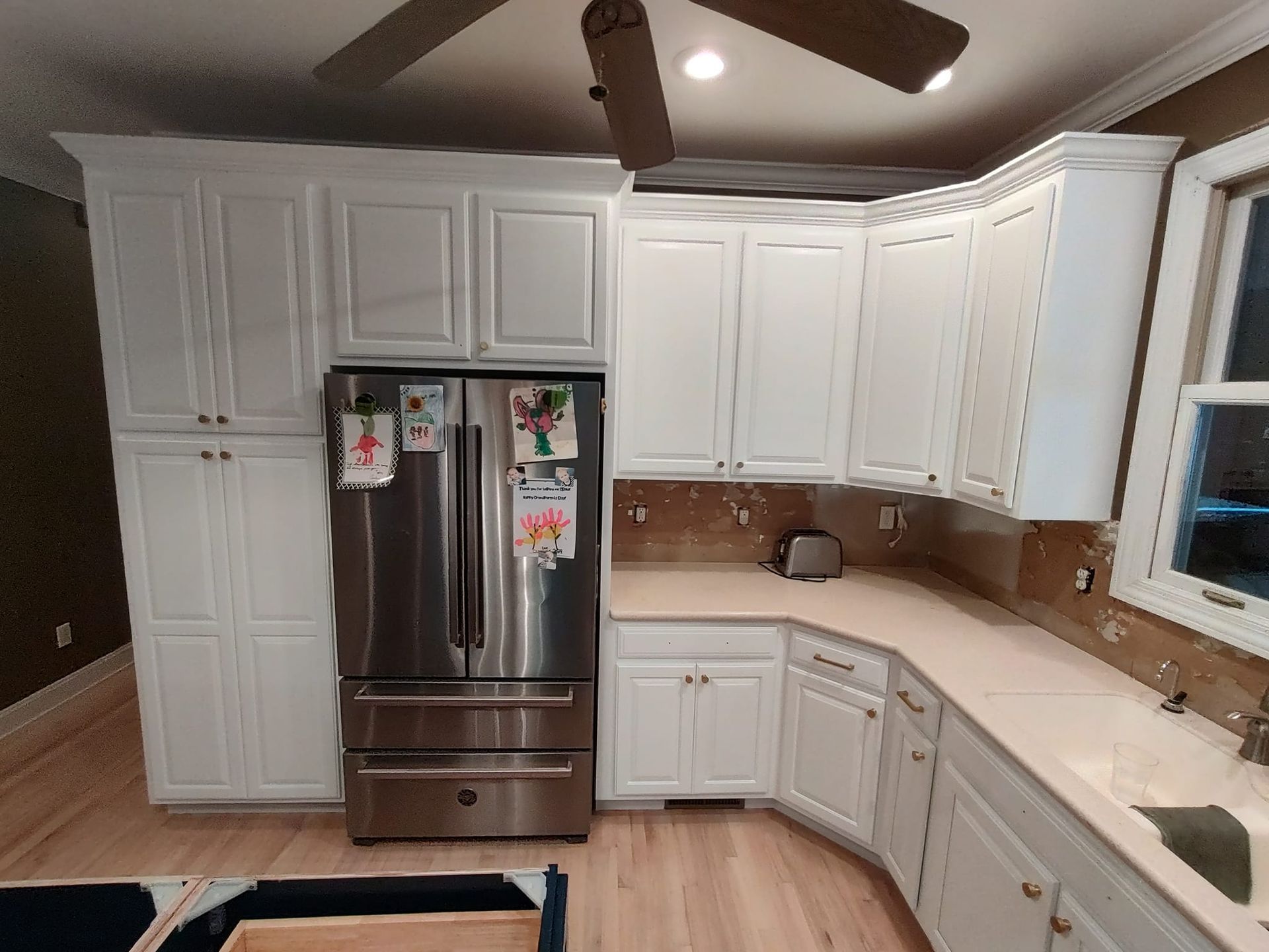 A kitchen with white cabinets and a stainless steel refrigerator