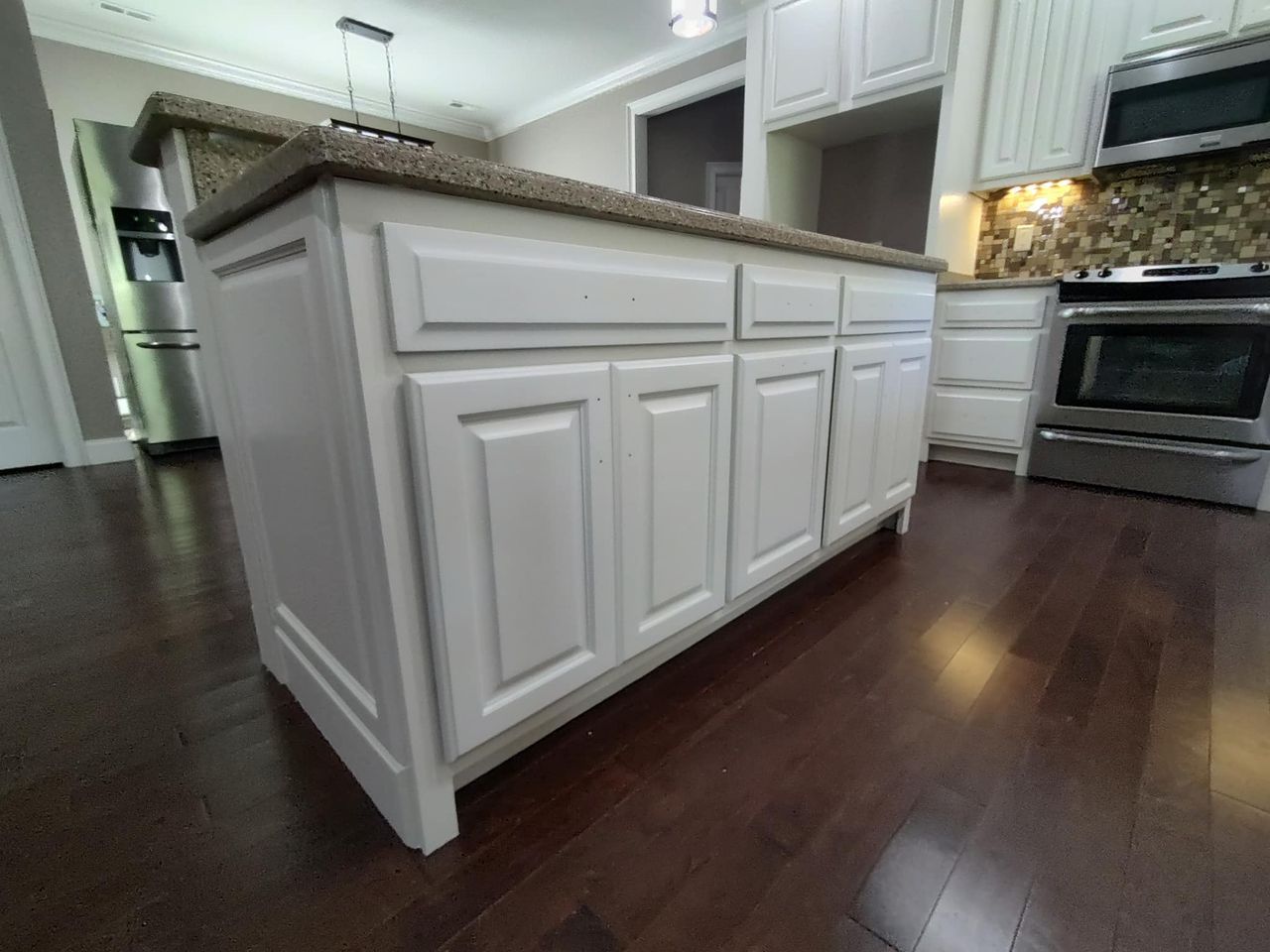 A kitchen with white cabinets , granite counter tops , and stainless steel appliances.