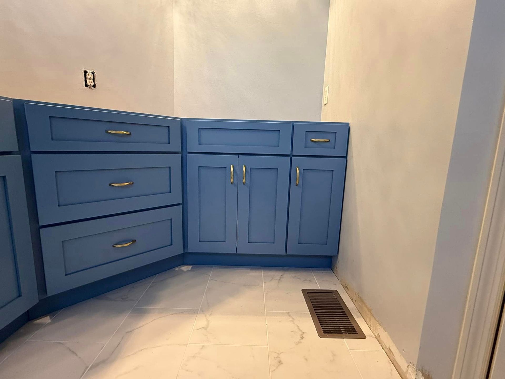 A kitchen with blue cabinets and drawers and a marble floor.