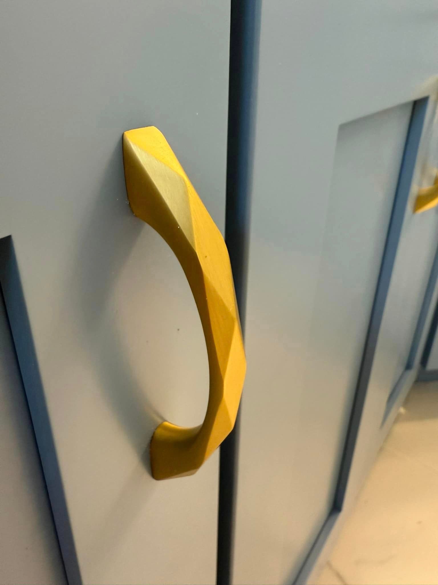 A close up of a yellow handle on a cabinet door.