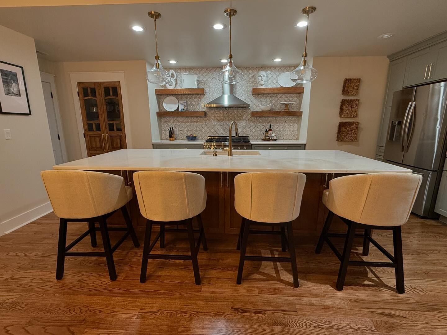 A kitchen with a large island and four chairs.