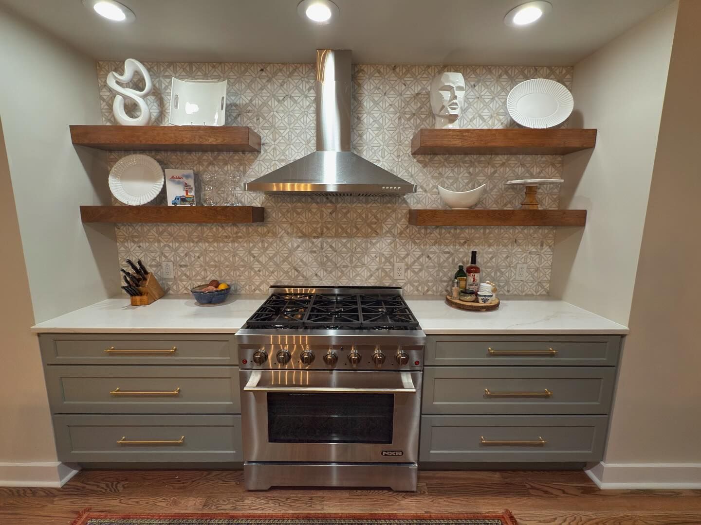 A kitchen with a stove , oven , and shelves.