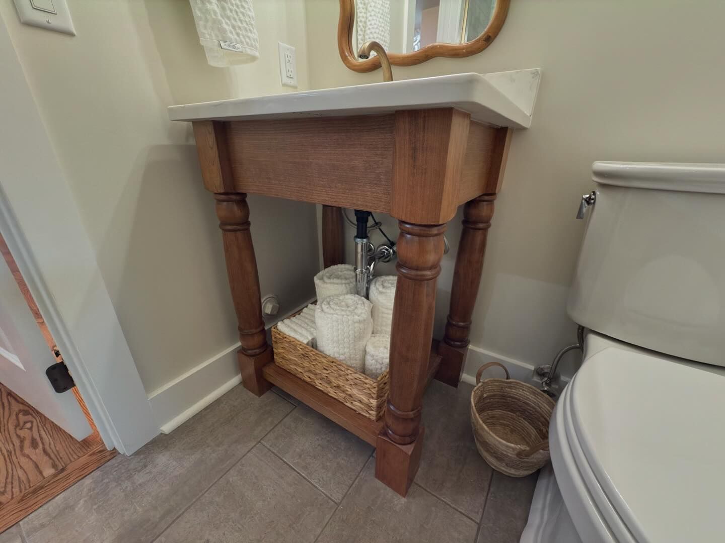 A bathroom with a wooden vanity , toilet and mirror.