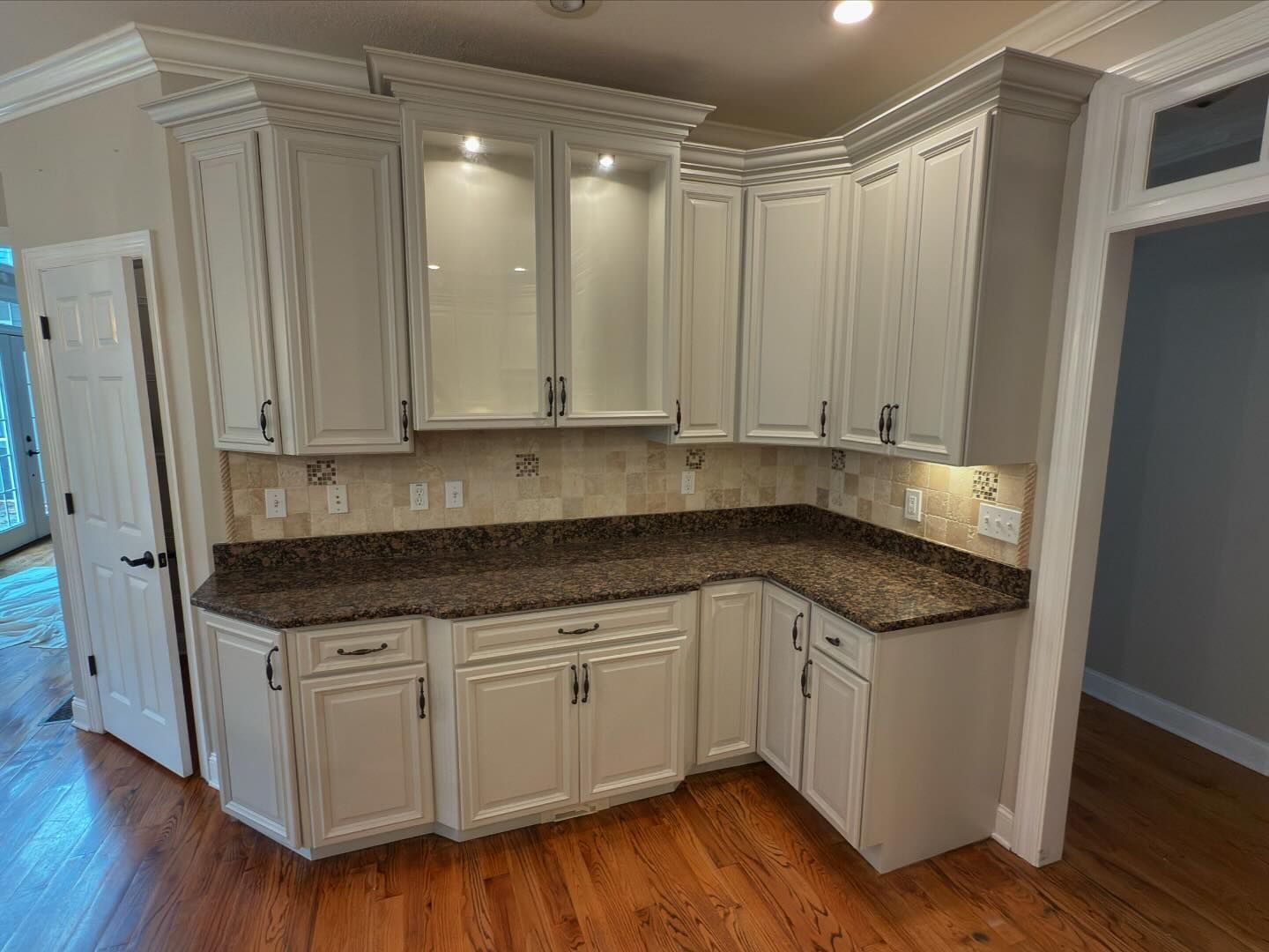 A kitchen with white cabinets , granite counter tops , and a stainless steel refrigerator.