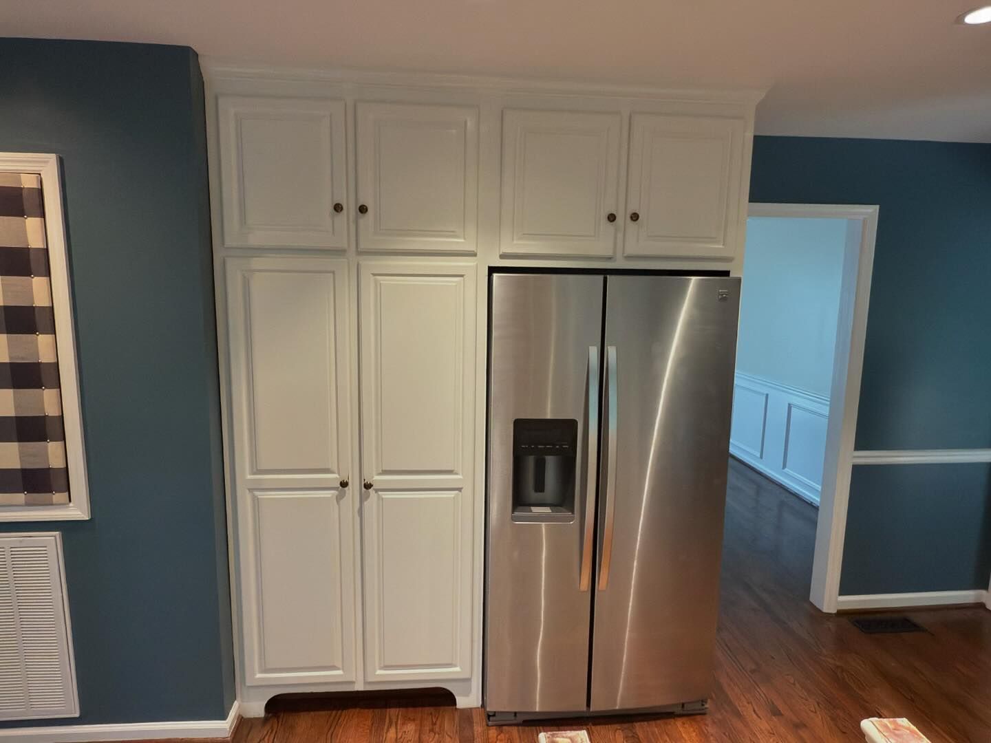 A kitchen with white cabinets and a stainless steel refrigerator