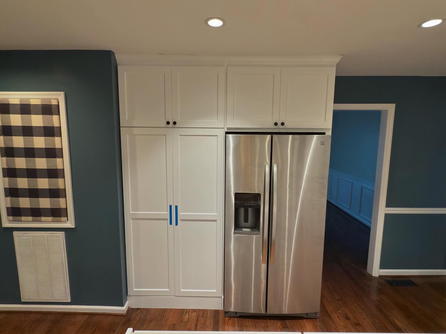 A kitchen with a stainless steel refrigerator and white cabinets