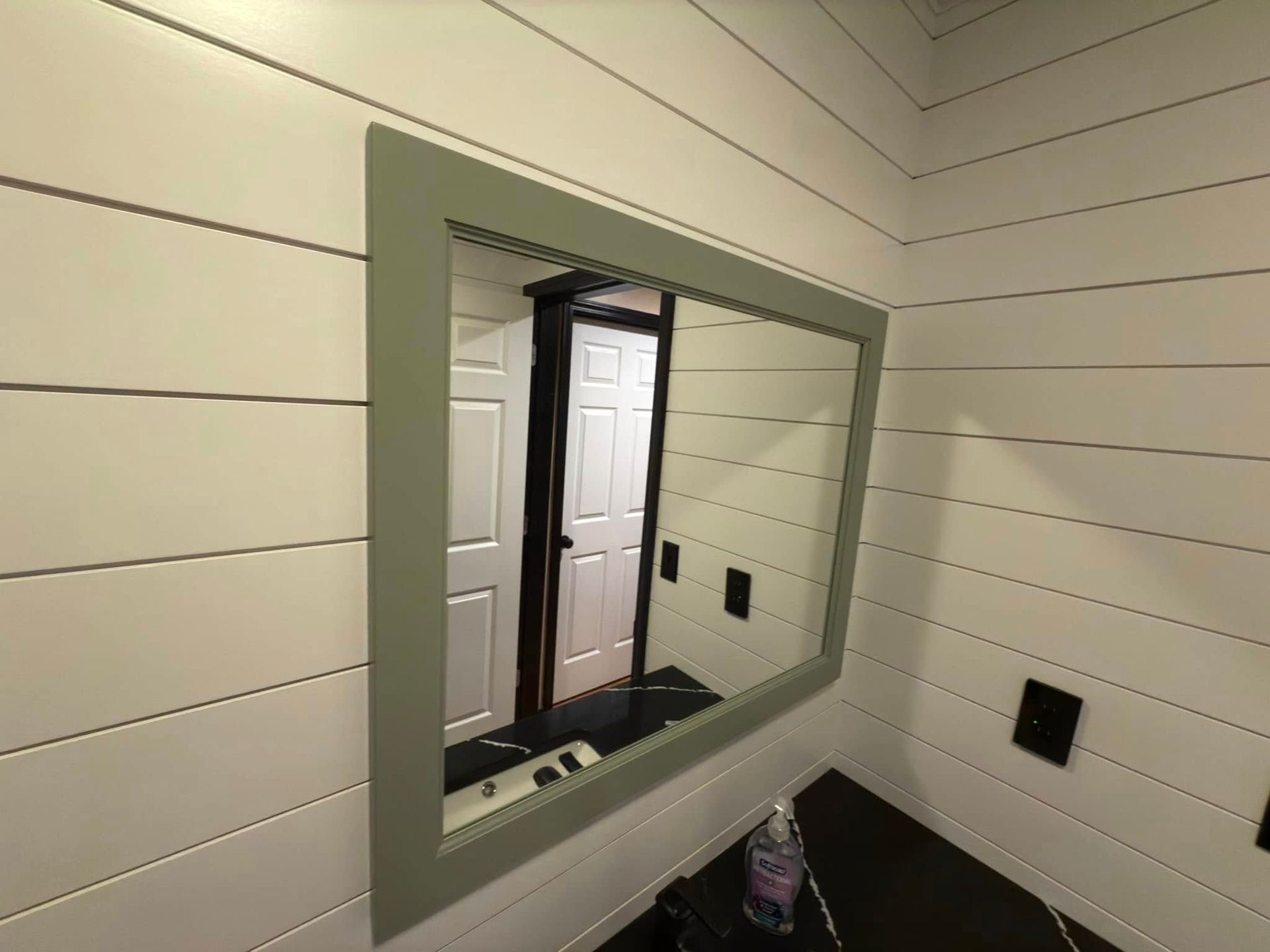 A large mirror is hanging on a white wall in a bathroom.