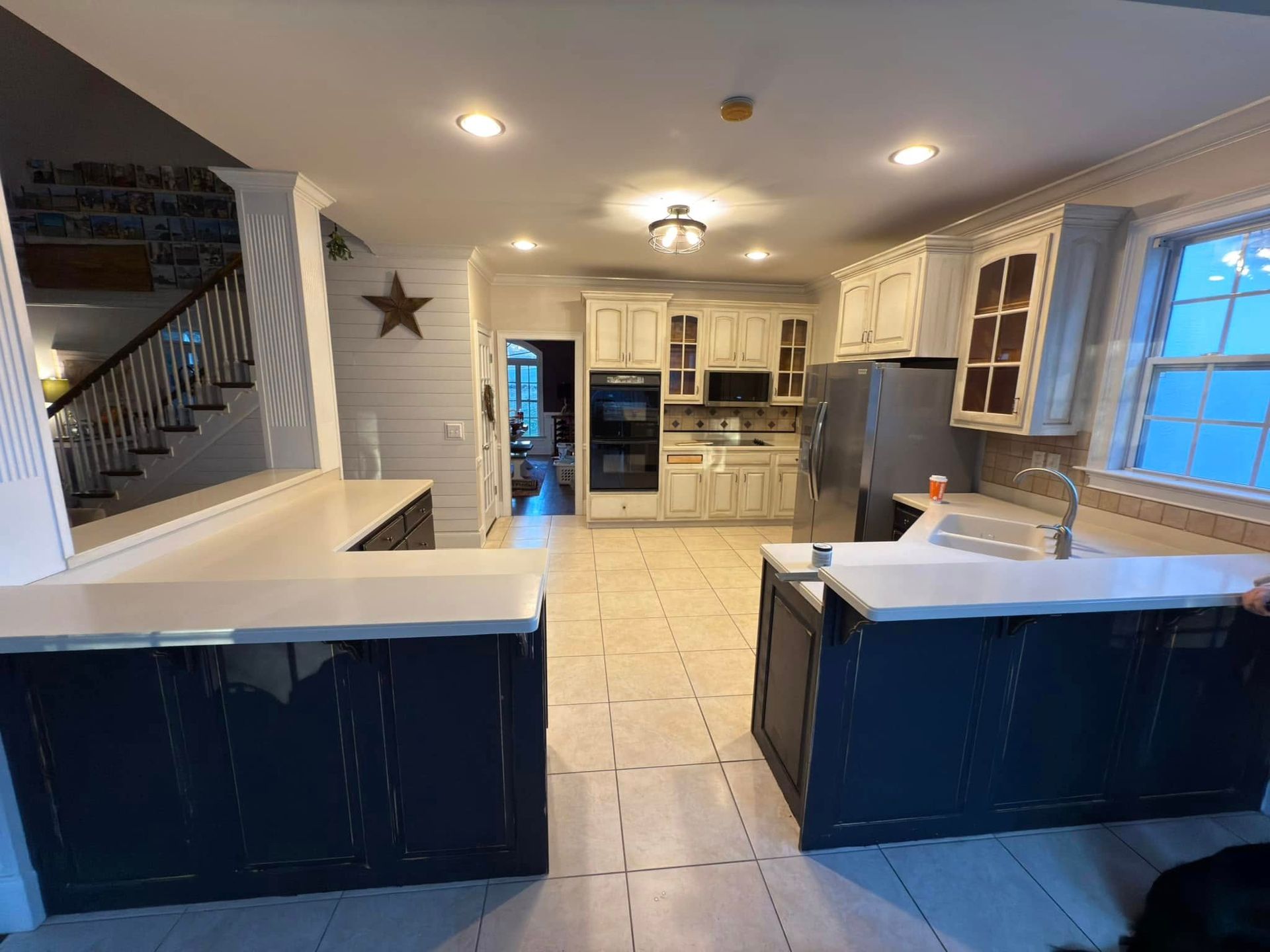 A kitchen with blue cabinets and a stainless steel refrigerator.