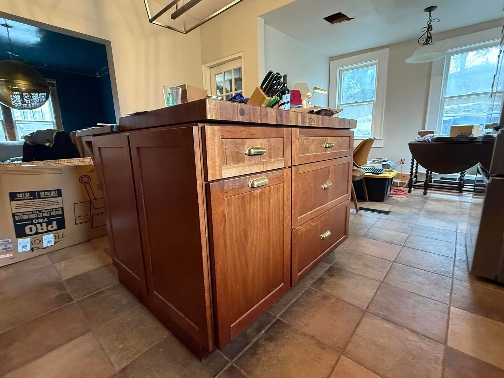 A kitchen island with drawers and a cutting board on top of it.