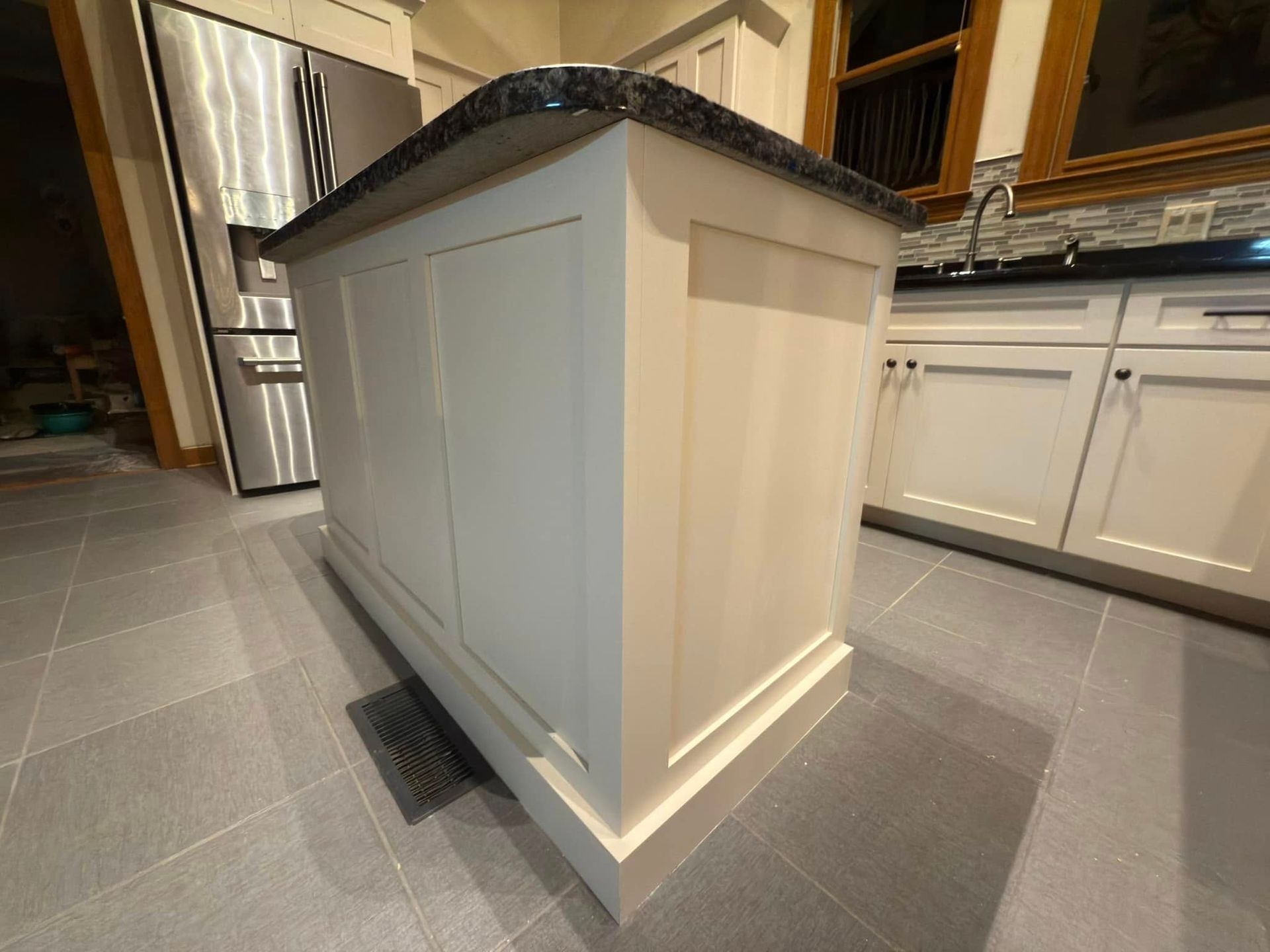 A kitchen with white cabinets and a black counter top.
