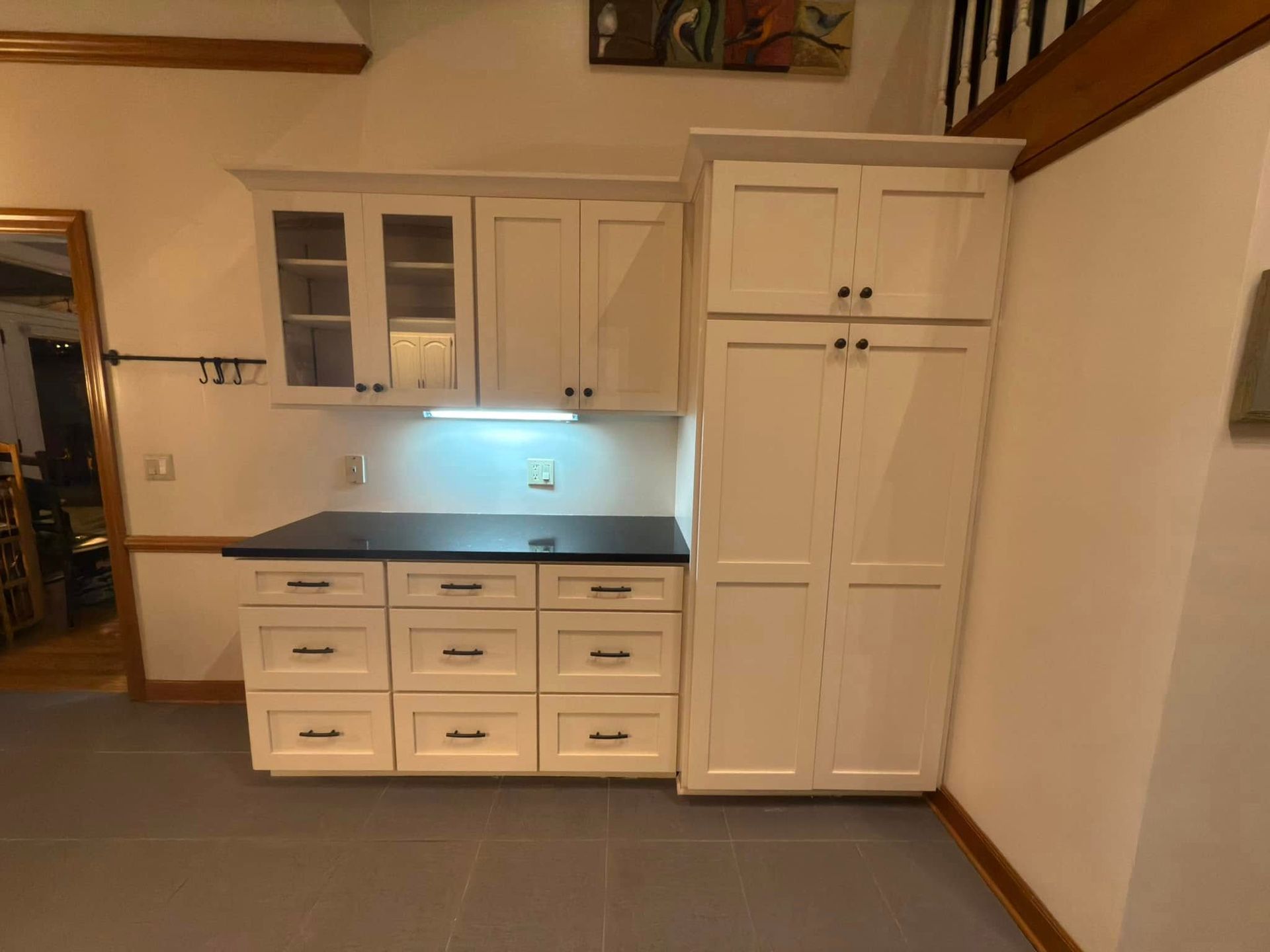 A kitchen with white cabinets and drawers and a black counter top.