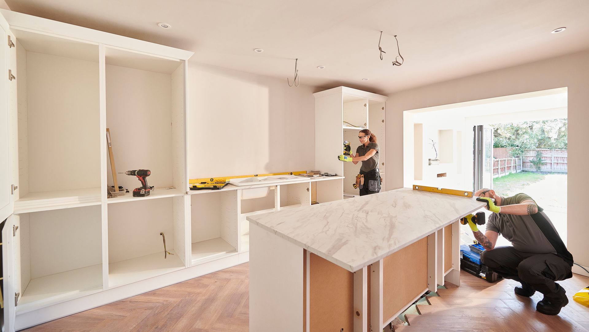 A man is measuring a counter in a kitchen.