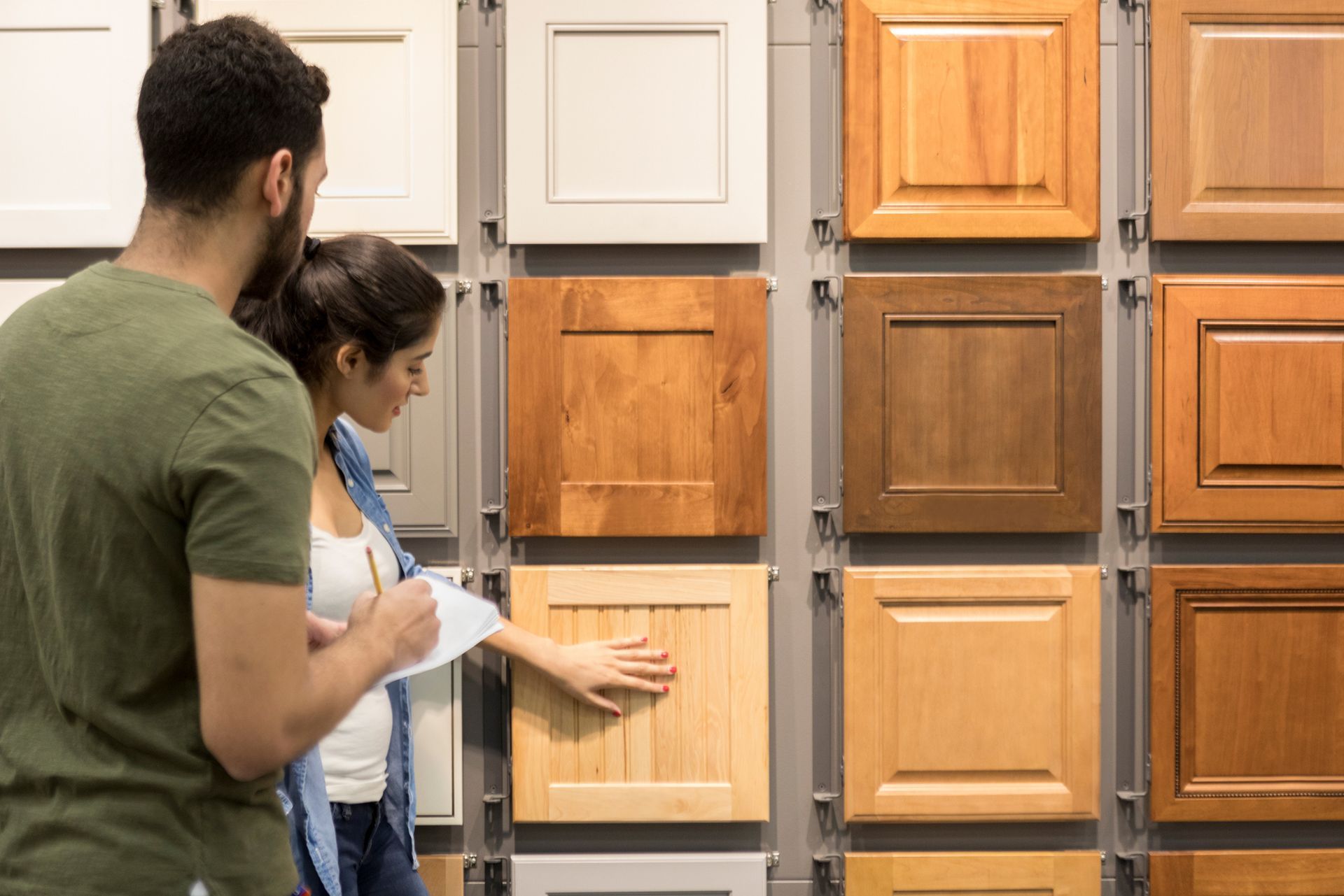 A man and a woman are looking at cabinet doors in a store.