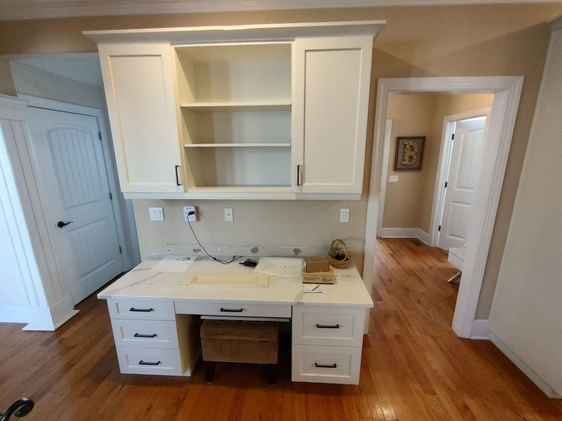 A room with hardwood floors and white cabinets with the letter b on the wall