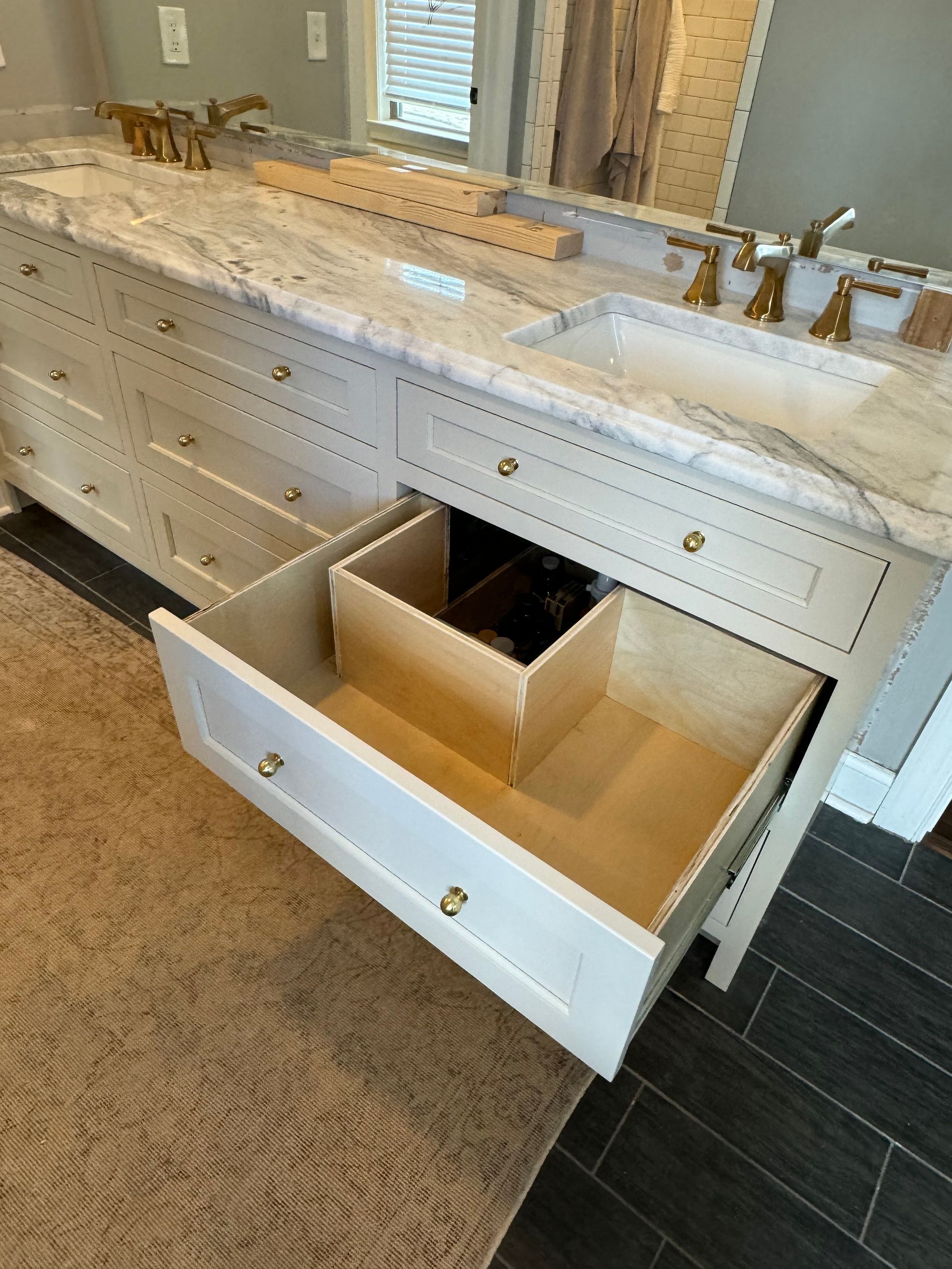 A bathroom vanity with two sinks and a drawer open.