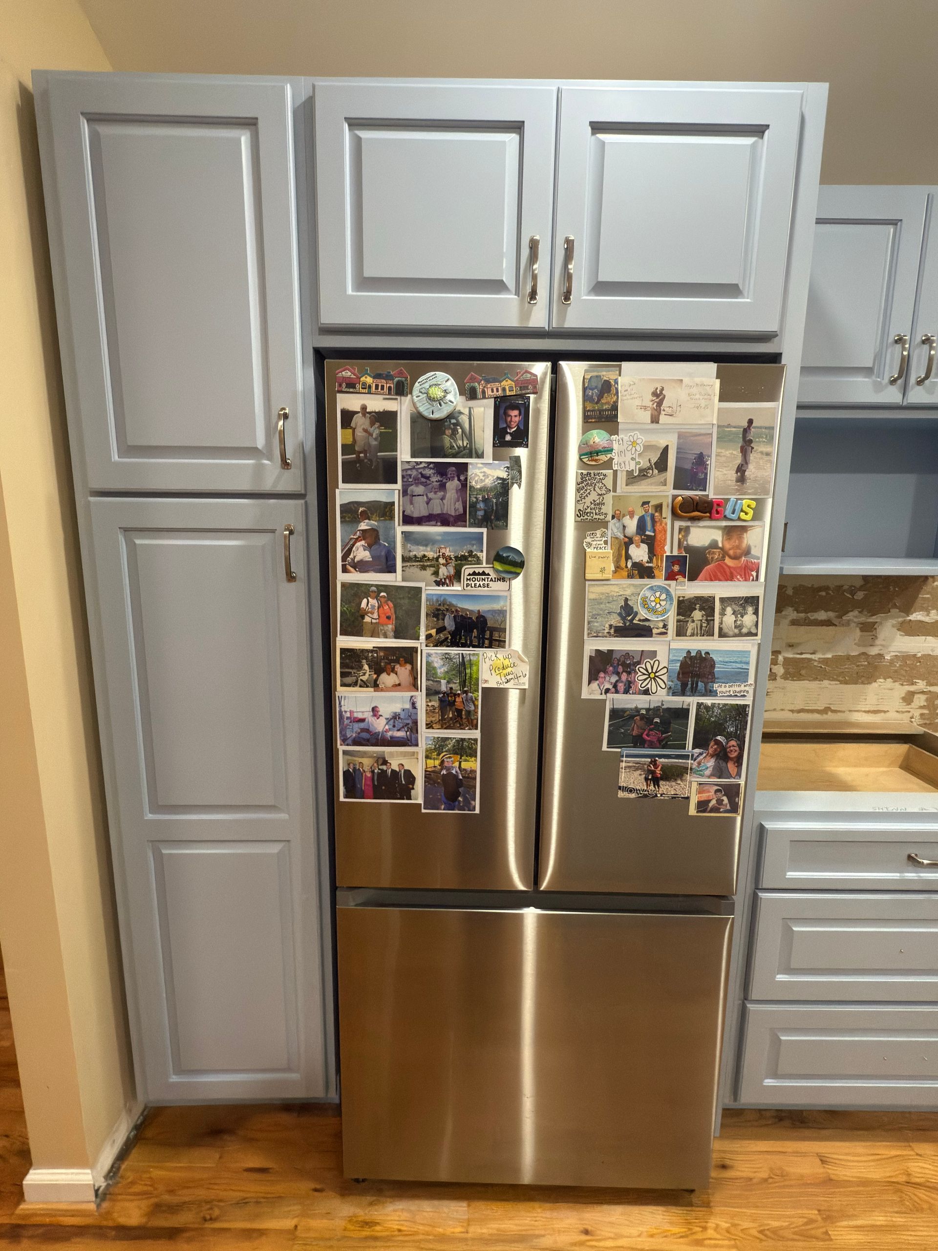 Refrigerator with photos, surrounded by blue kitchen cabinets.