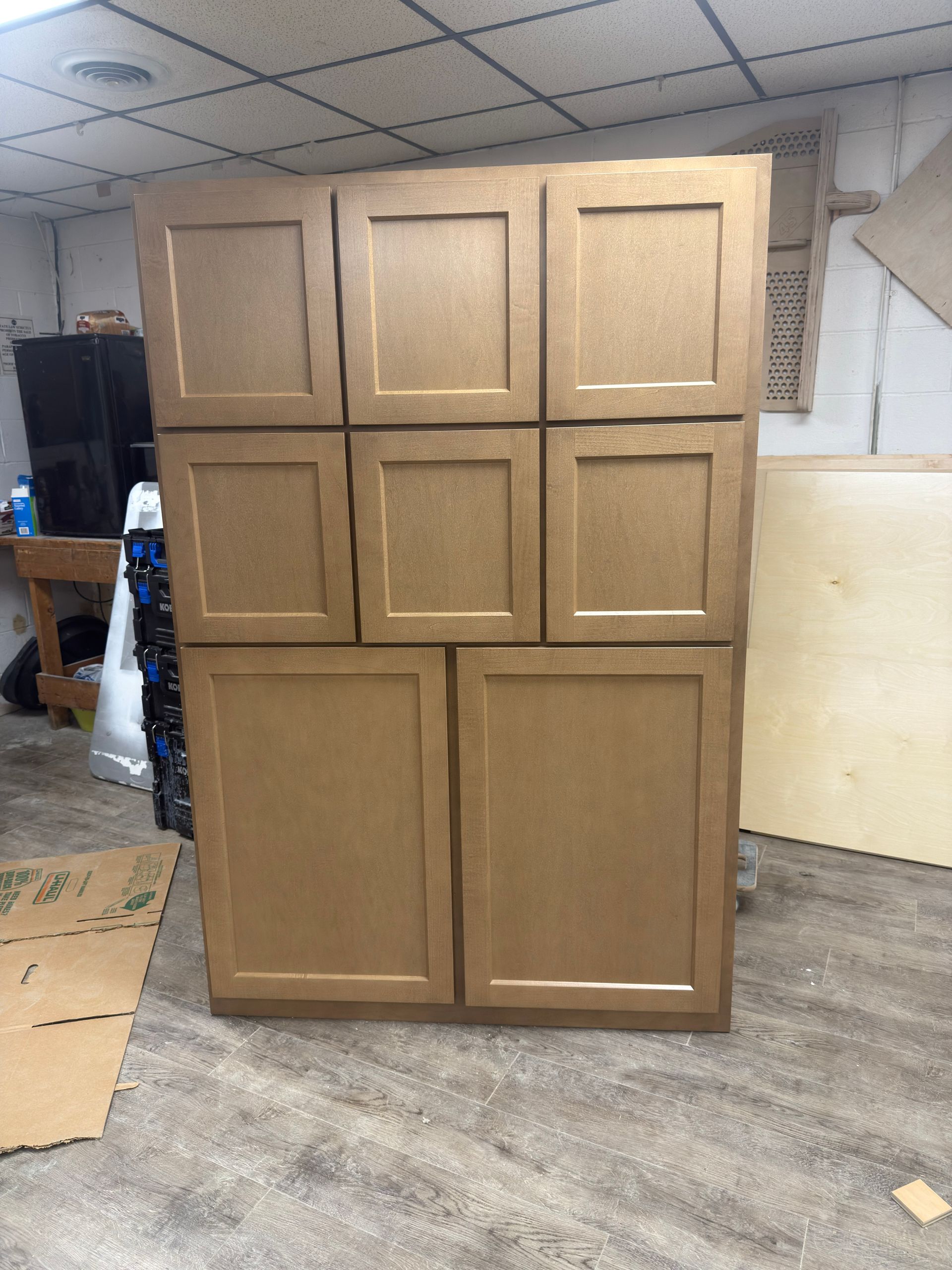A large, beige cabinet with multiple doors in a room with a concrete floor.