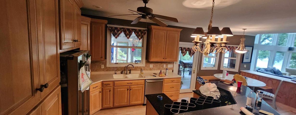 A kitchen with wooden cabinets , stainless steel appliances and a ceiling fan.