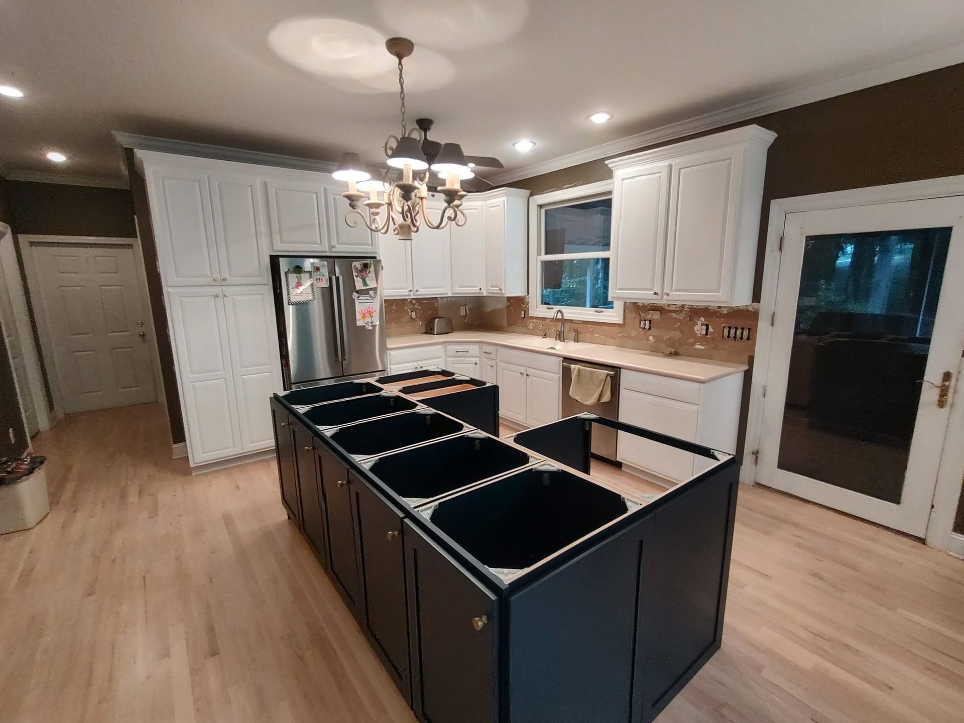 A kitchen with white cabinets and black sinks and a large island in the middle.