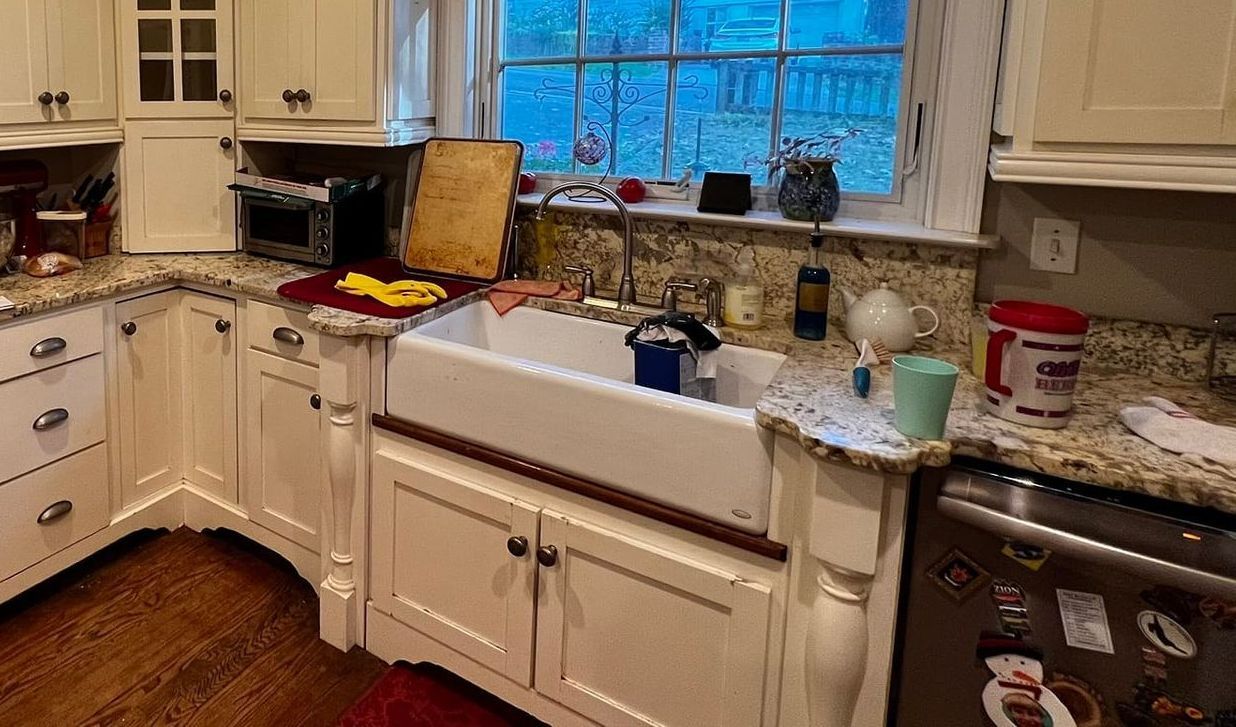 A kitchen with white cabinets , granite counter tops , a sink and a window.