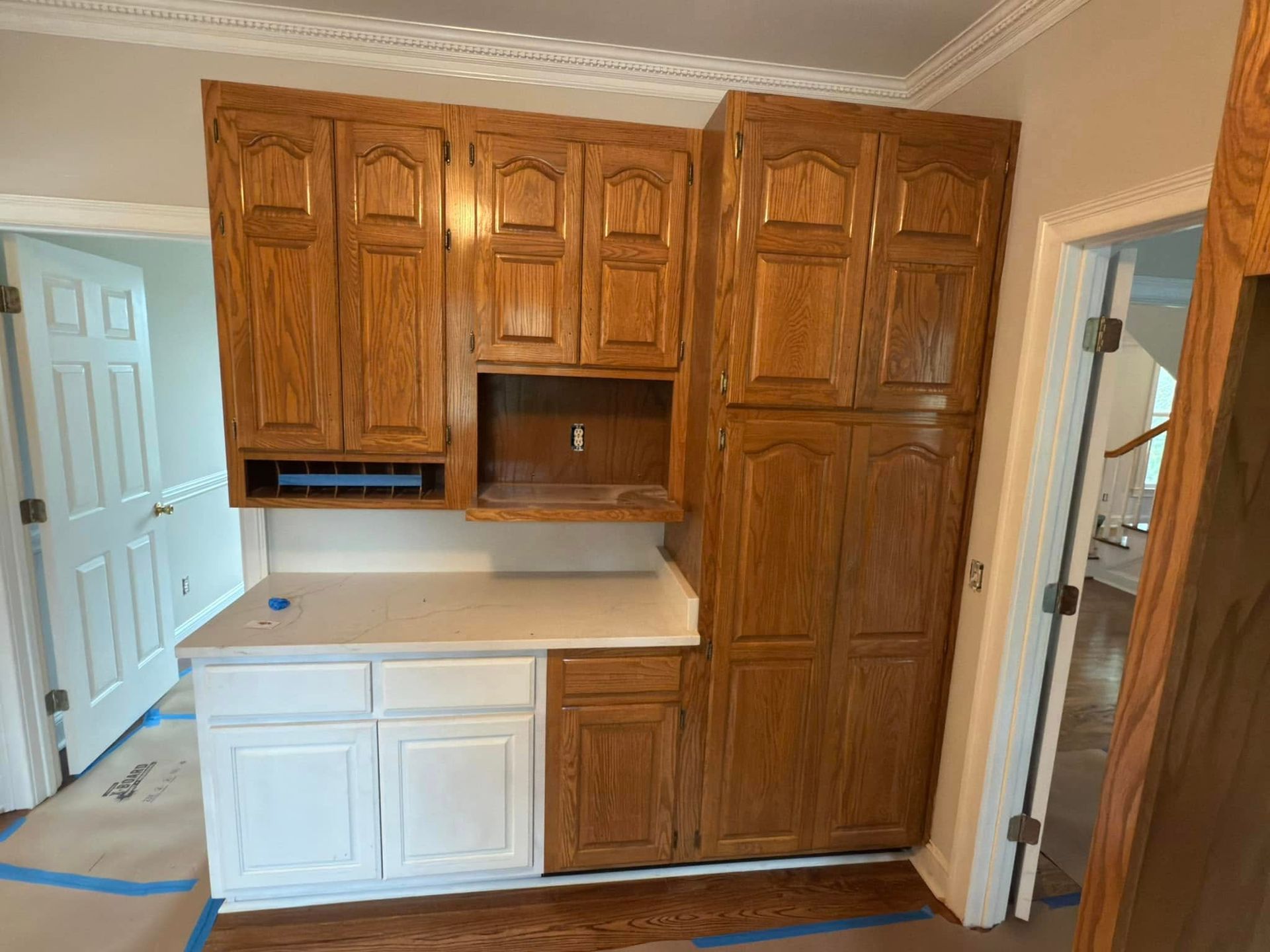 A kitchen with wooden cabinets and white counter tops is being painted.