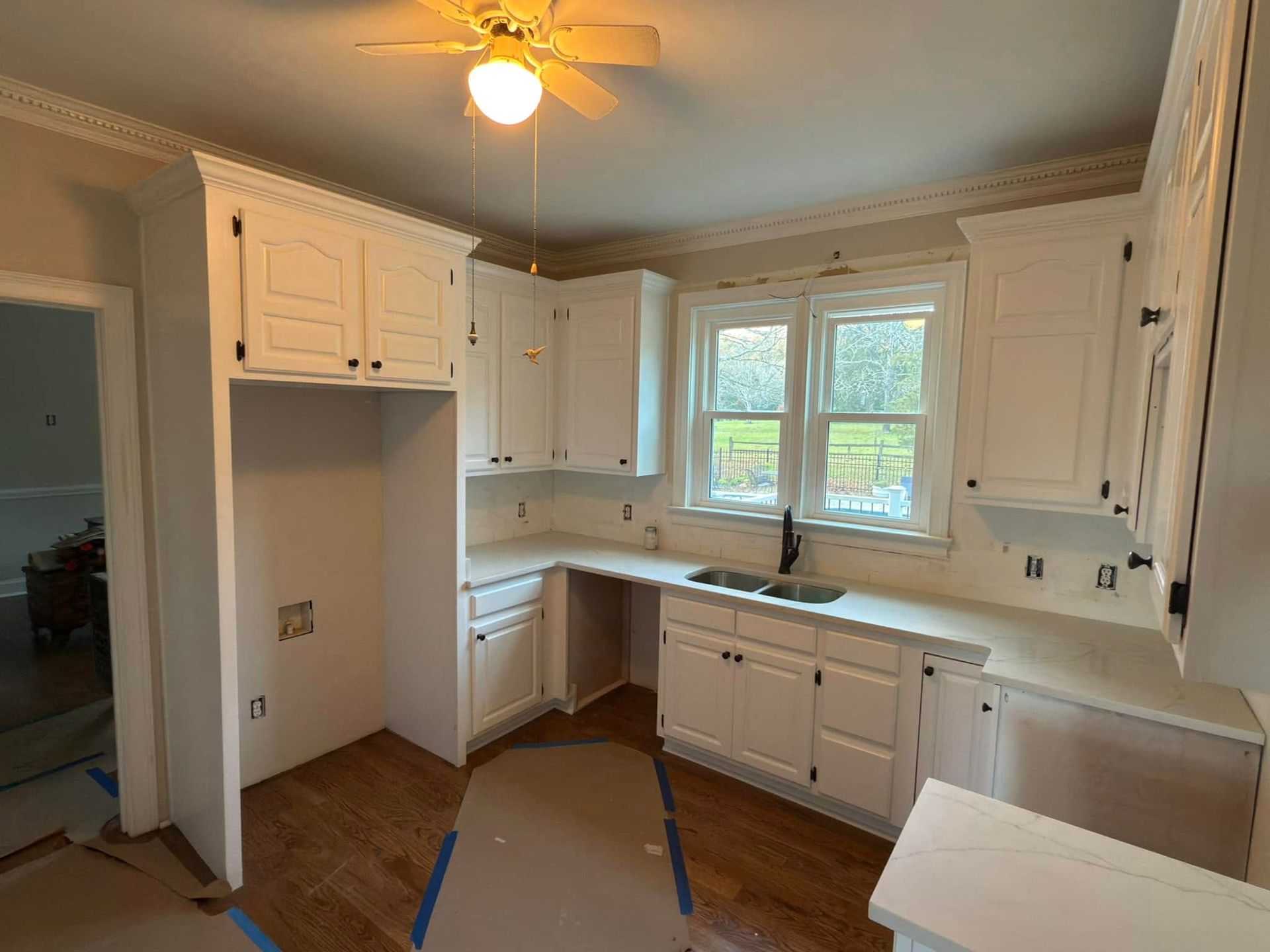 A kitchen with white cabinets and a ceiling fan.